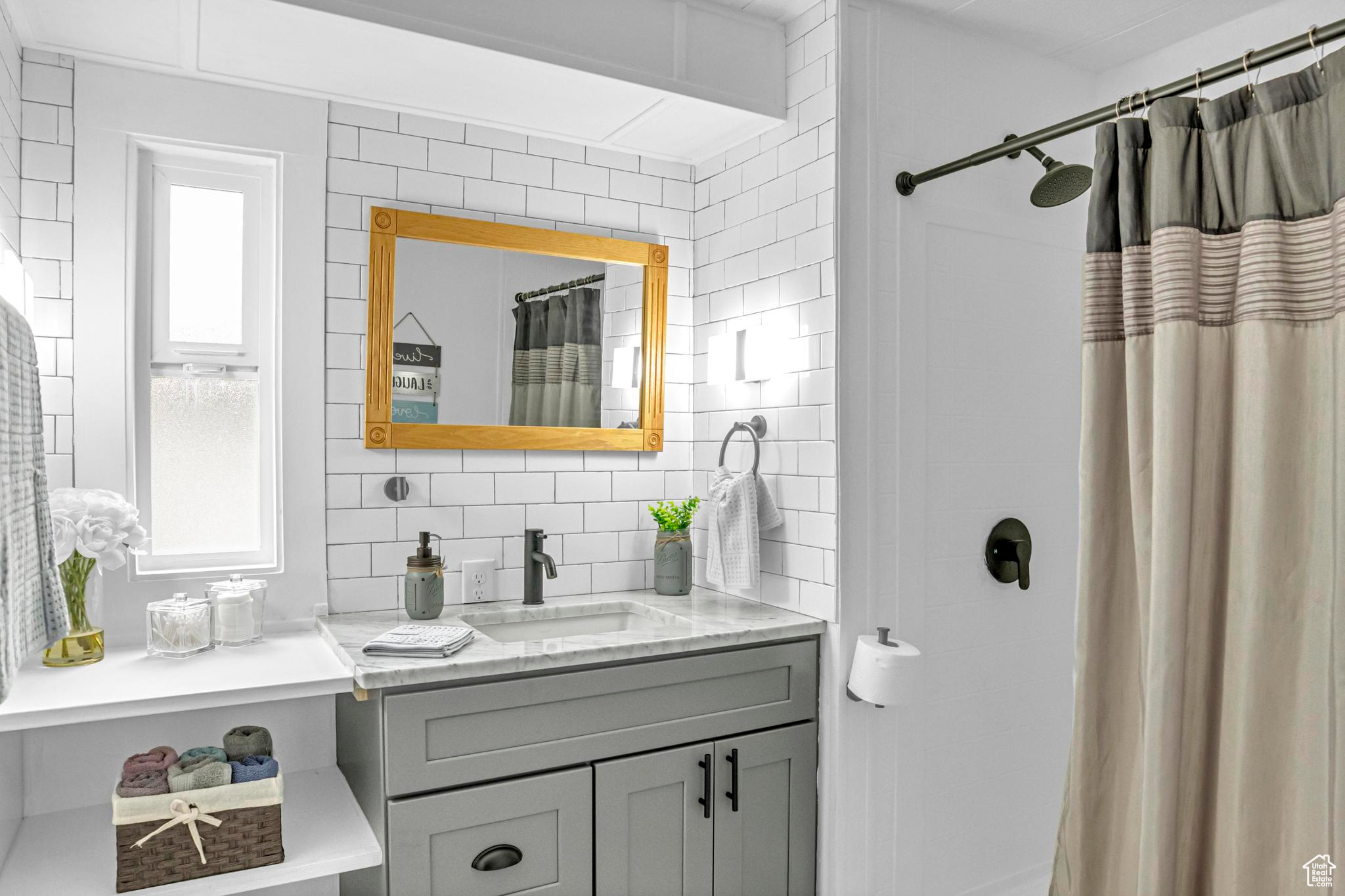 Bathroom featuring backsplash, oversized vanity, and tile walls