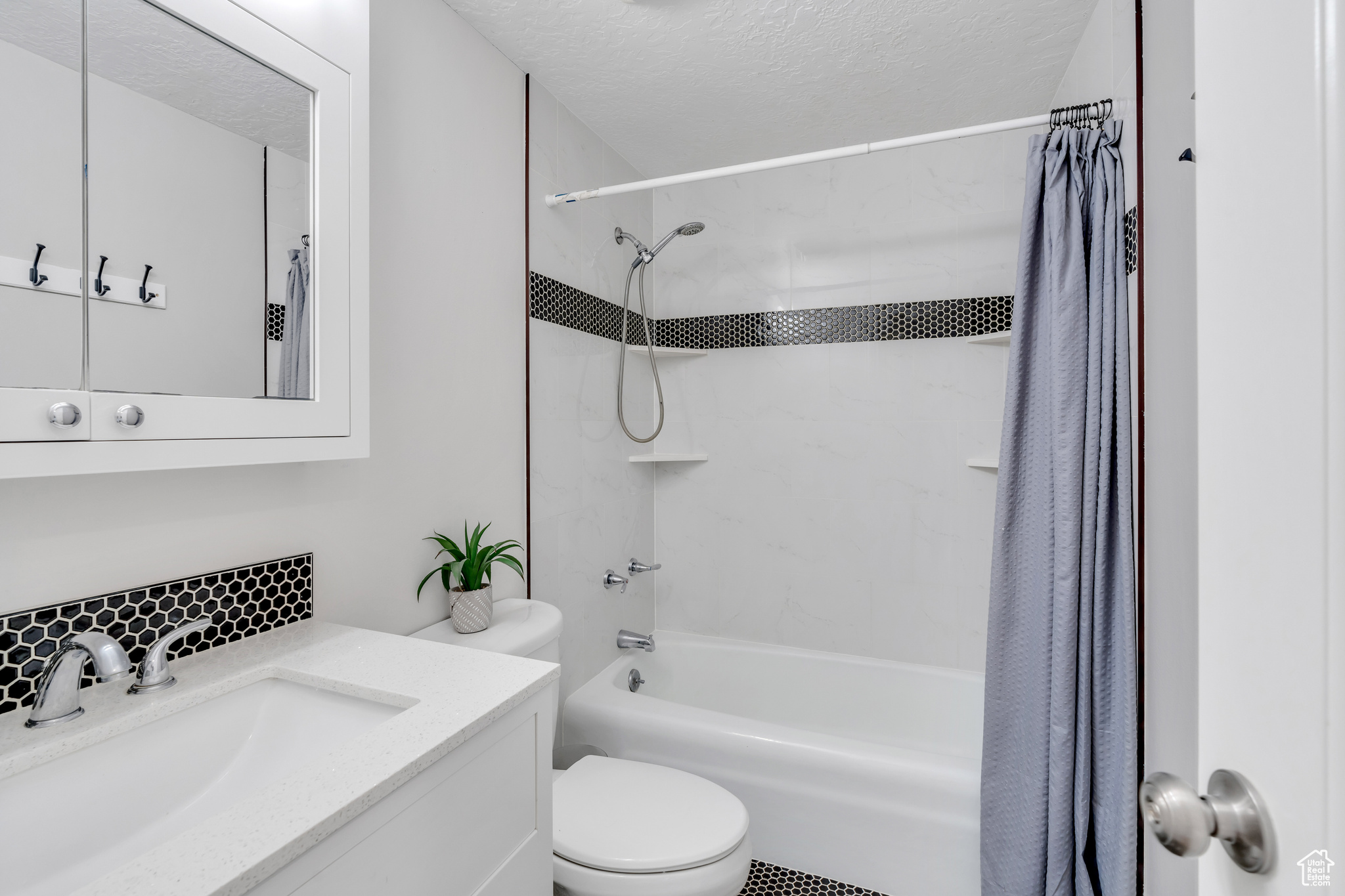 Full bathroom featuring a textured ceiling, shower / tub combo, toilet, and oversized vanity