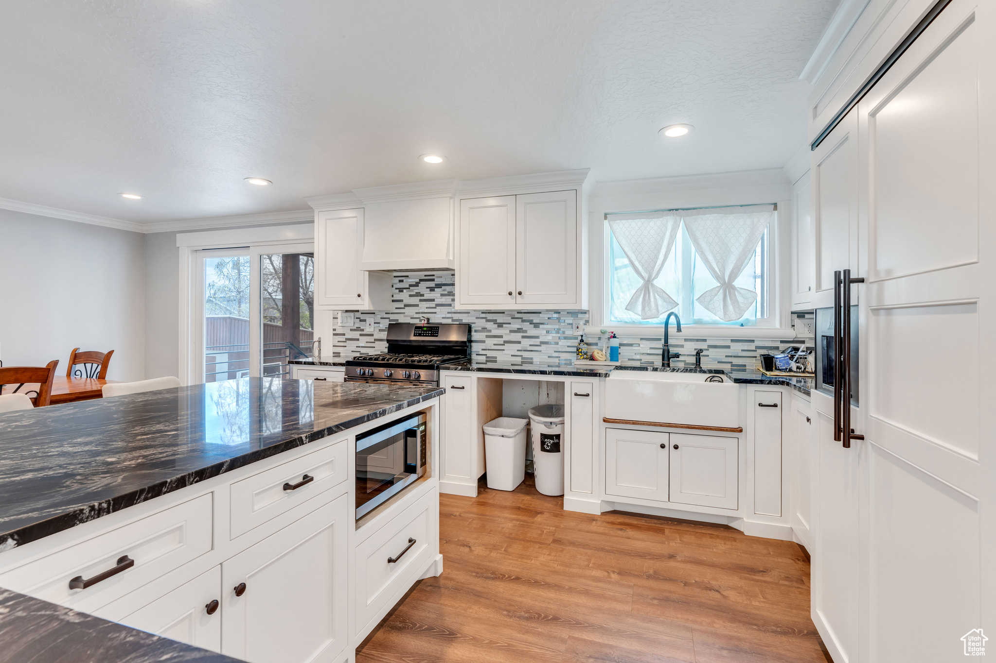 Kitchen featuring appliances with stainless steel finishes, light hardwood / wood-style floors, white cabinetry, sink, and ornamental molding