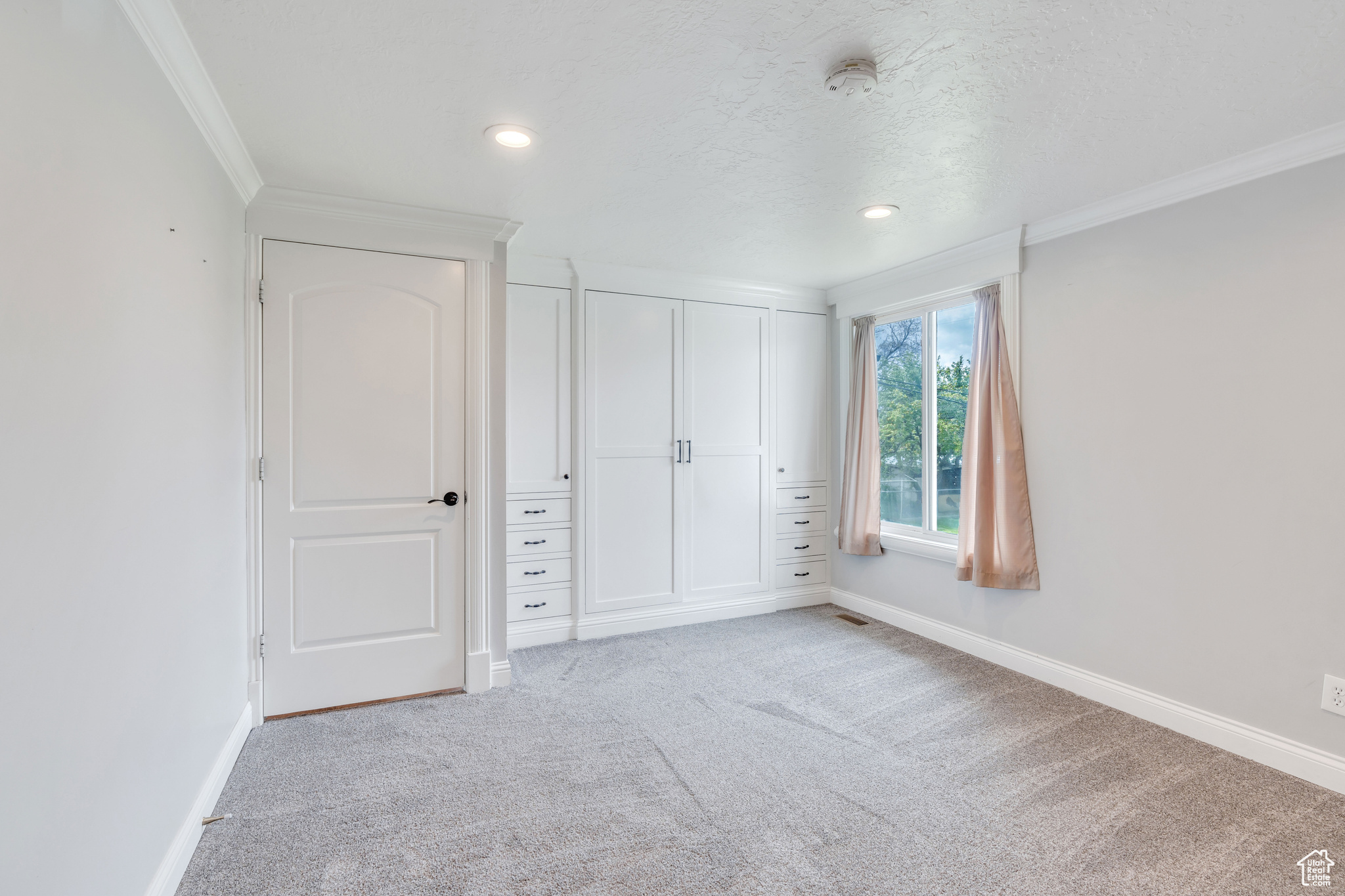Unfurnished bedroom with crown molding and light colored carpet