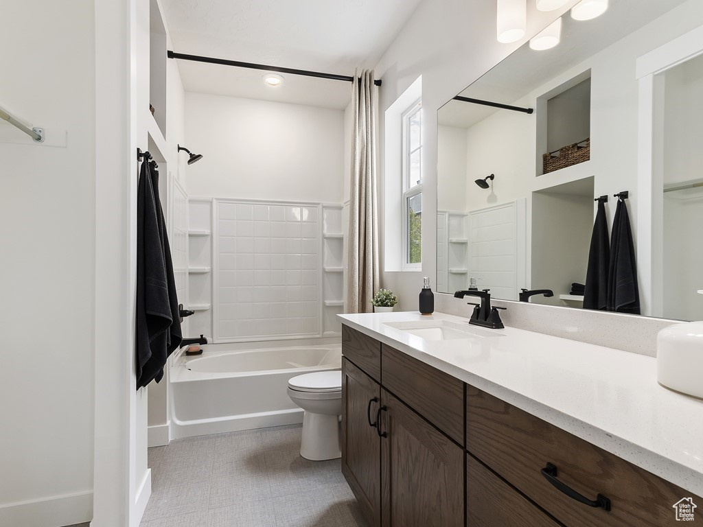 Full bathroom featuring vanity with extensive cabinet space, toilet, tile floors, and  shower combination