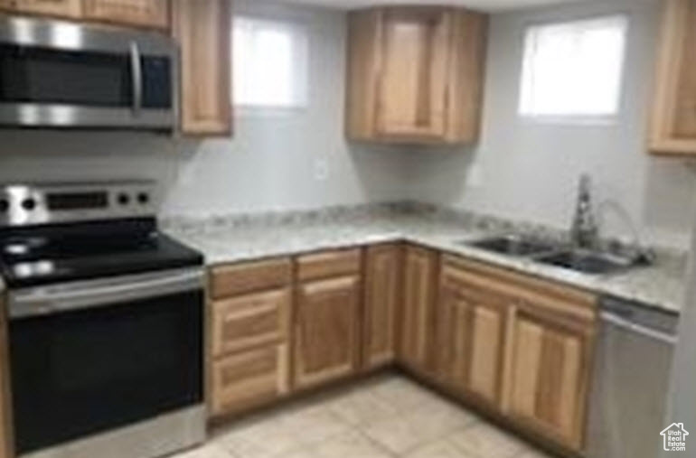 Basement  Kitchen featuring sink, appliances with stainless steel finishes, a healthy amount of sunlight, and light tile floors