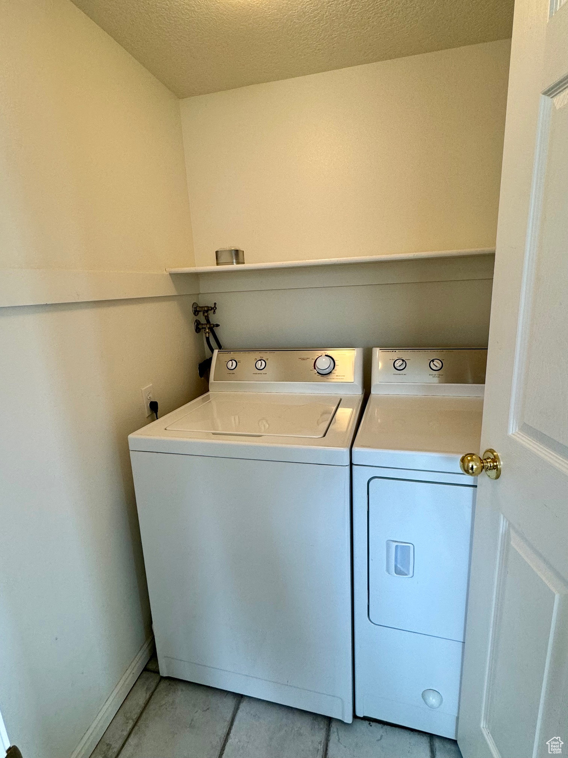 Laundry area featuring a textured ceiling, washing machine and dryer, and light tile floors