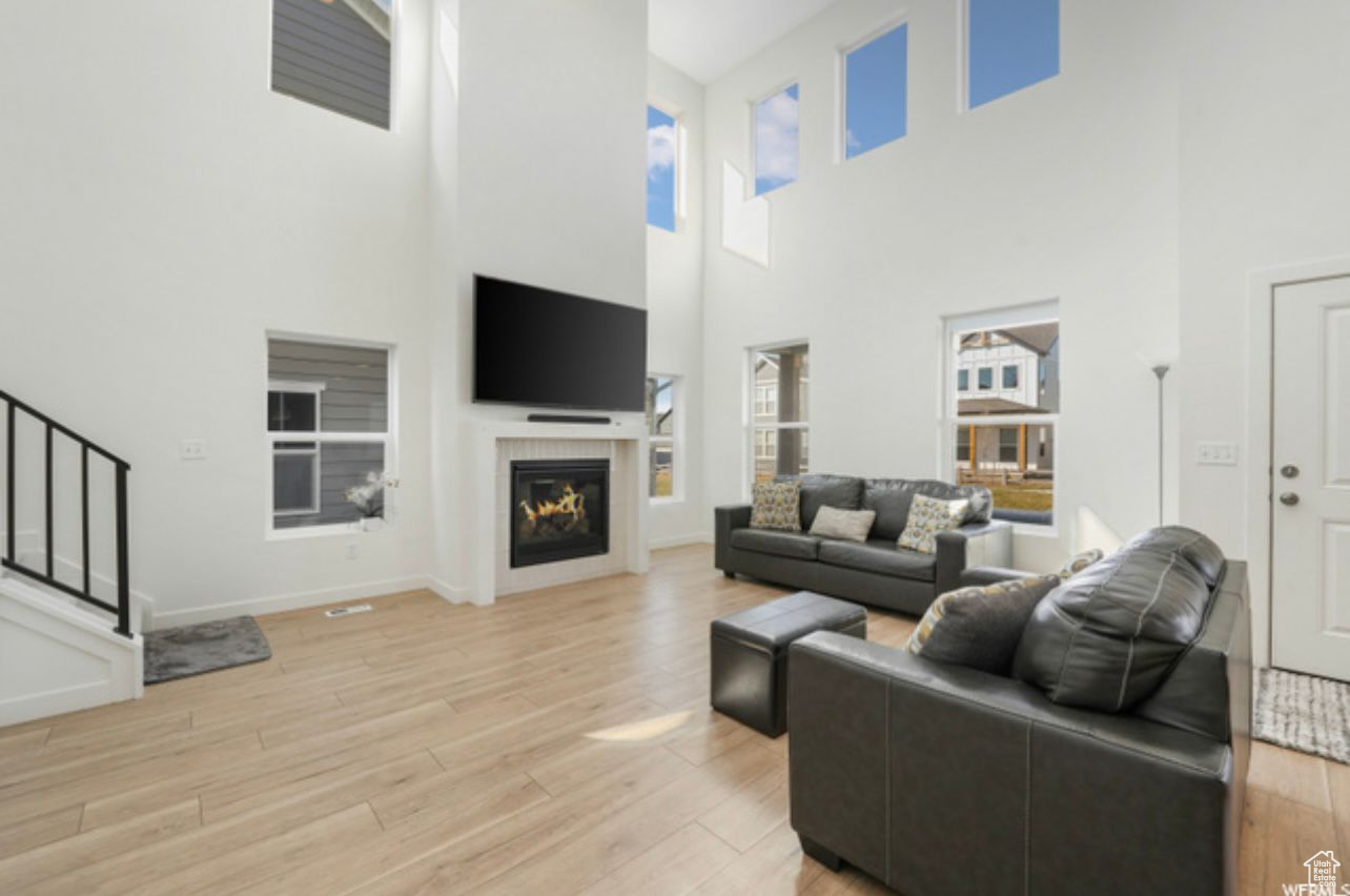 Living room with a towering ceiling and light hardwood / wood-style floors