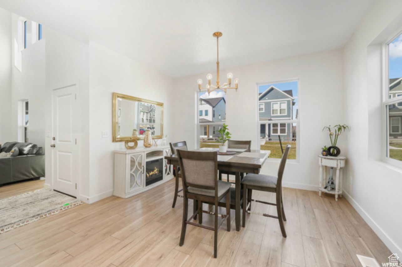 Dining room with an inviting chandelier, a healthy amount of sunlight, and light hardwood / wood-style flooring