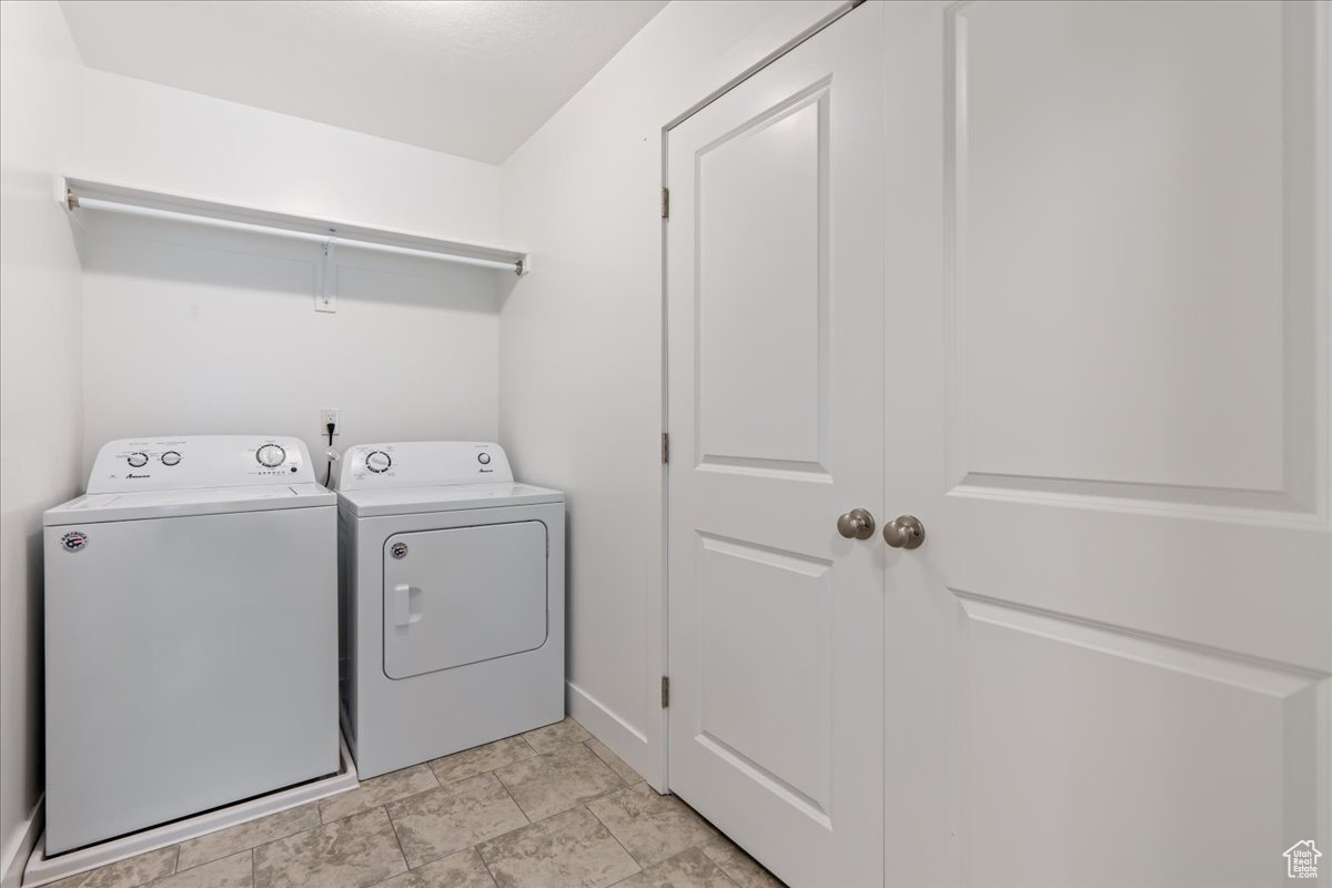 Washroom featuring washing machine and clothes dryer and light tile flooring