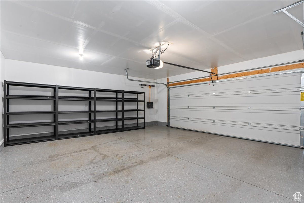 Two car garage featuring a garage door opener. Sturdy built in shelving and tool organizing system.