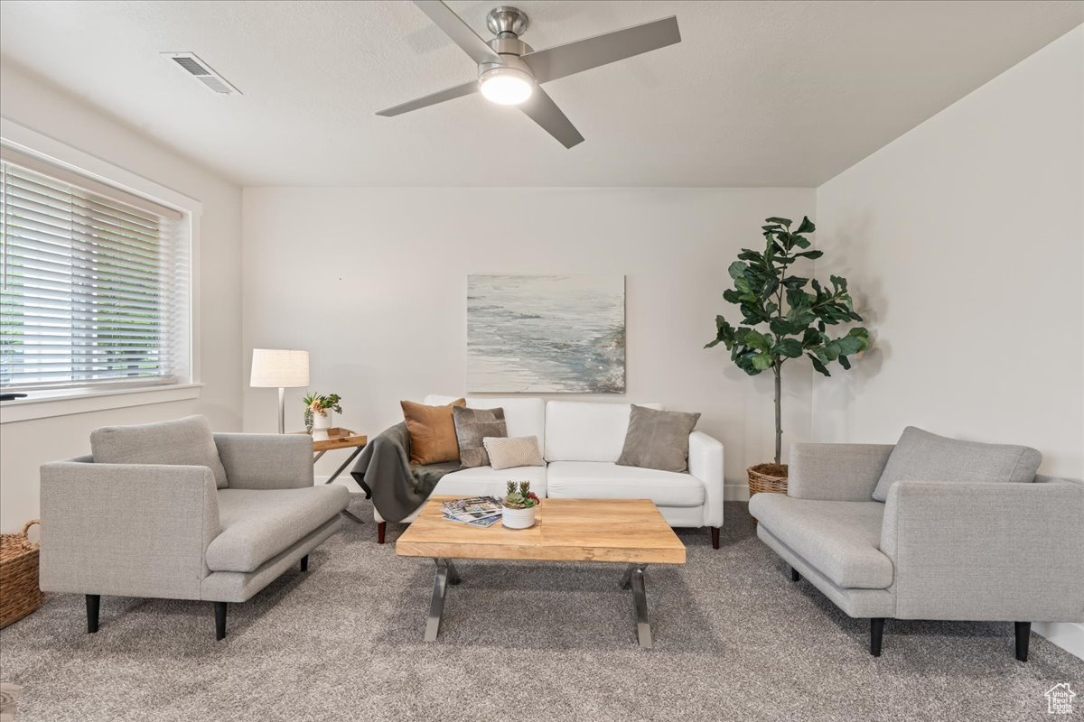 Living room with carpet flooring and ceiling fan