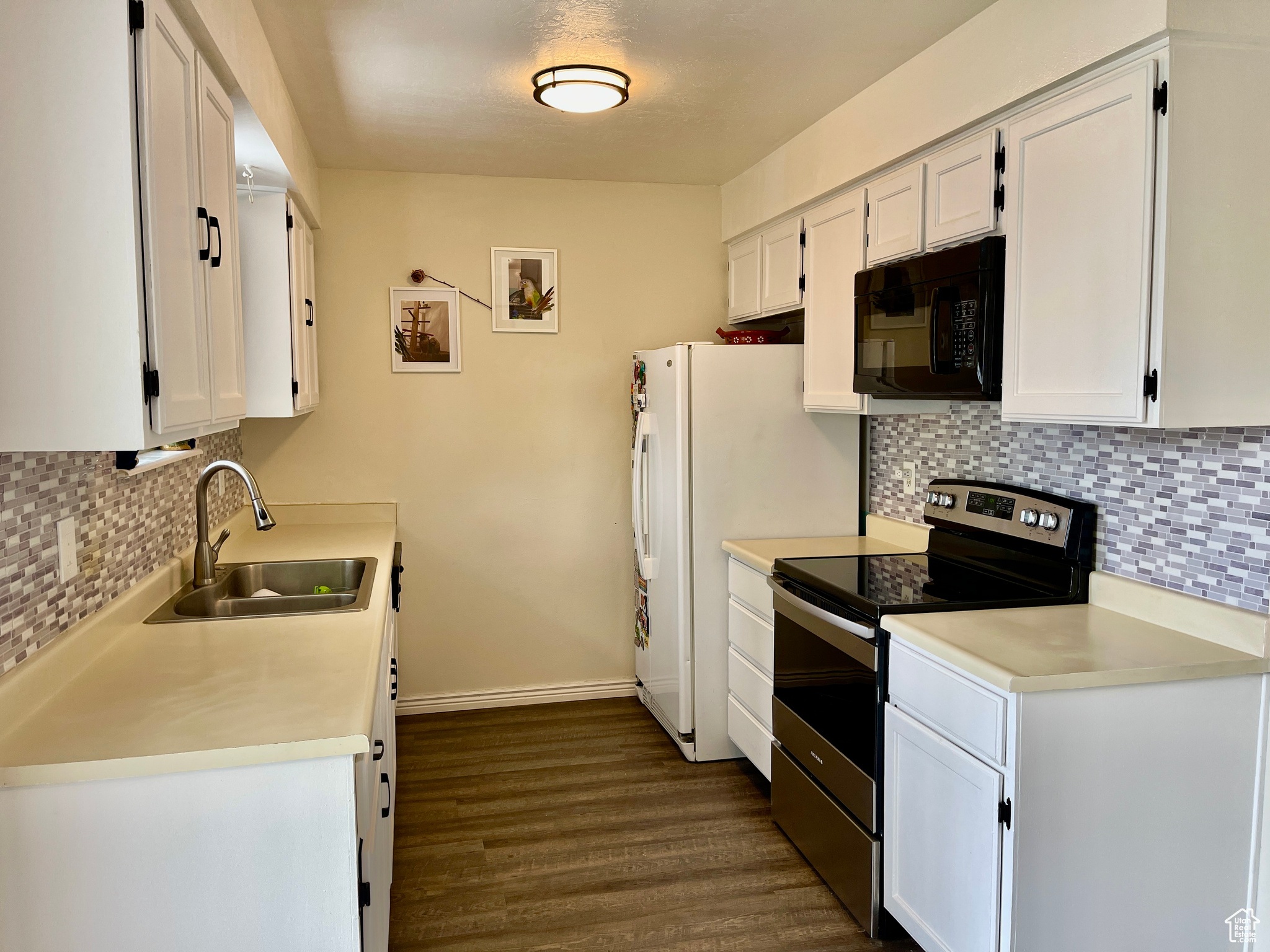 Kitchen with white cabinets, sink, tasteful backsplash, stainless steel electric range oven, and dark hardwood / wood-style floors