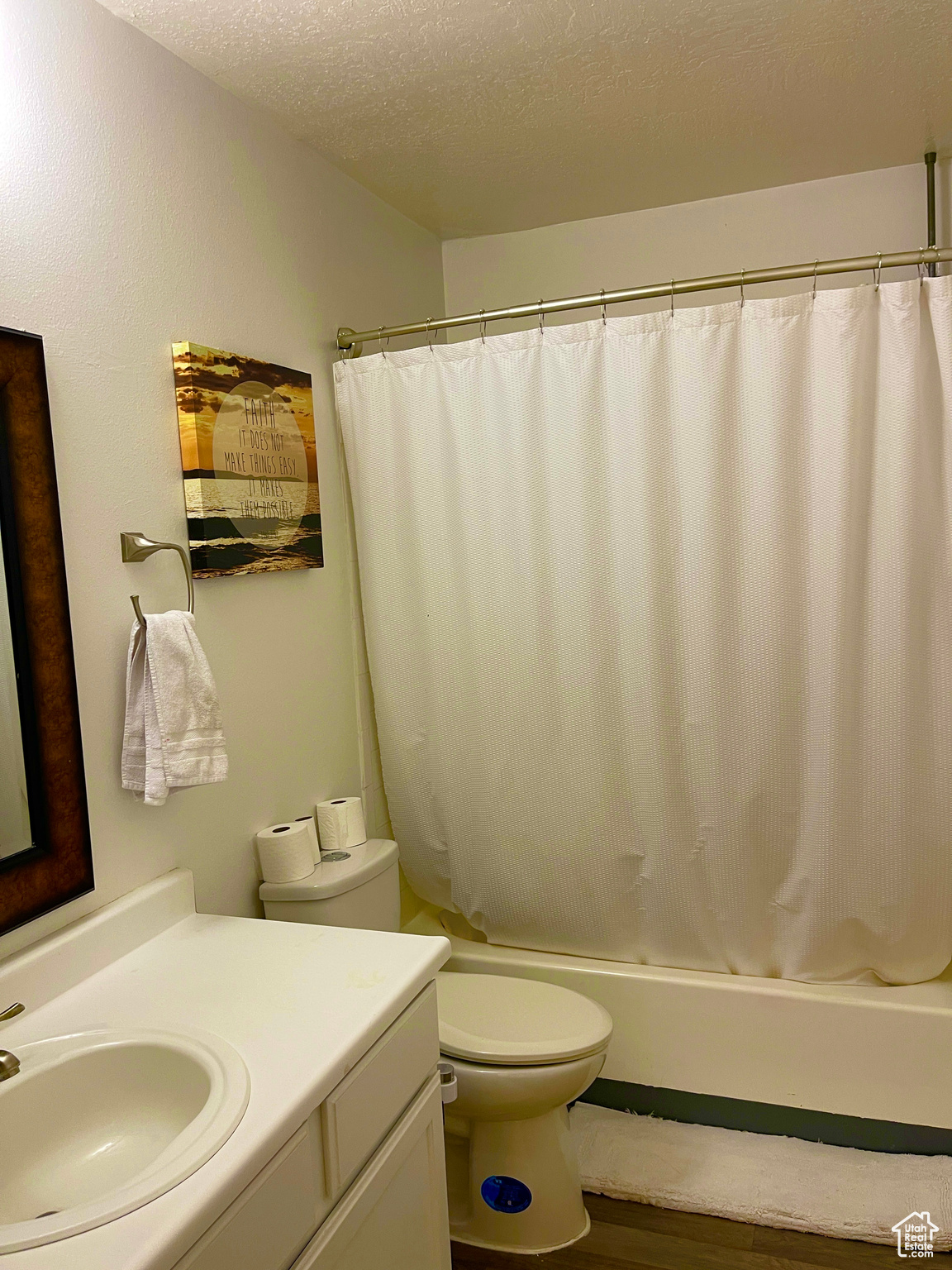 Full bathroom with wood-type flooring, shower / bath combo with shower curtain, vanity, toilet, and a textured ceiling