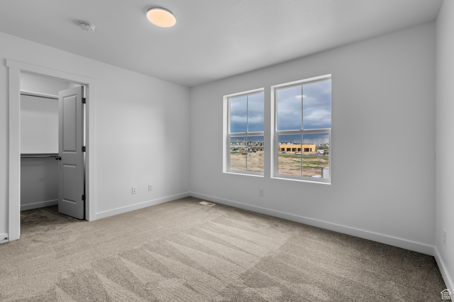 Unfurnished bedroom featuring carpet, a closet, a walk in closet, and a water view