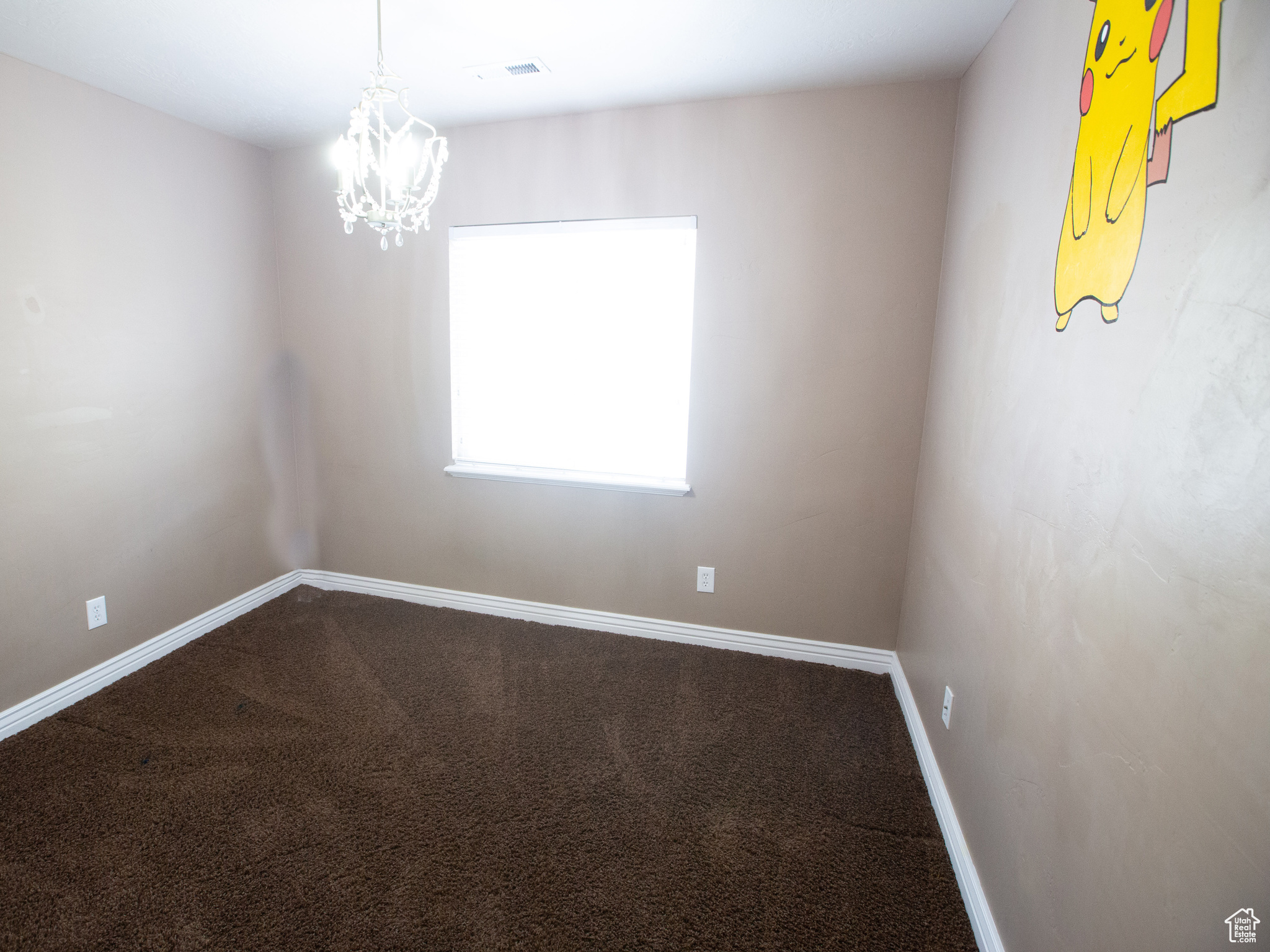 Carpeted spare room with an inviting chandelier