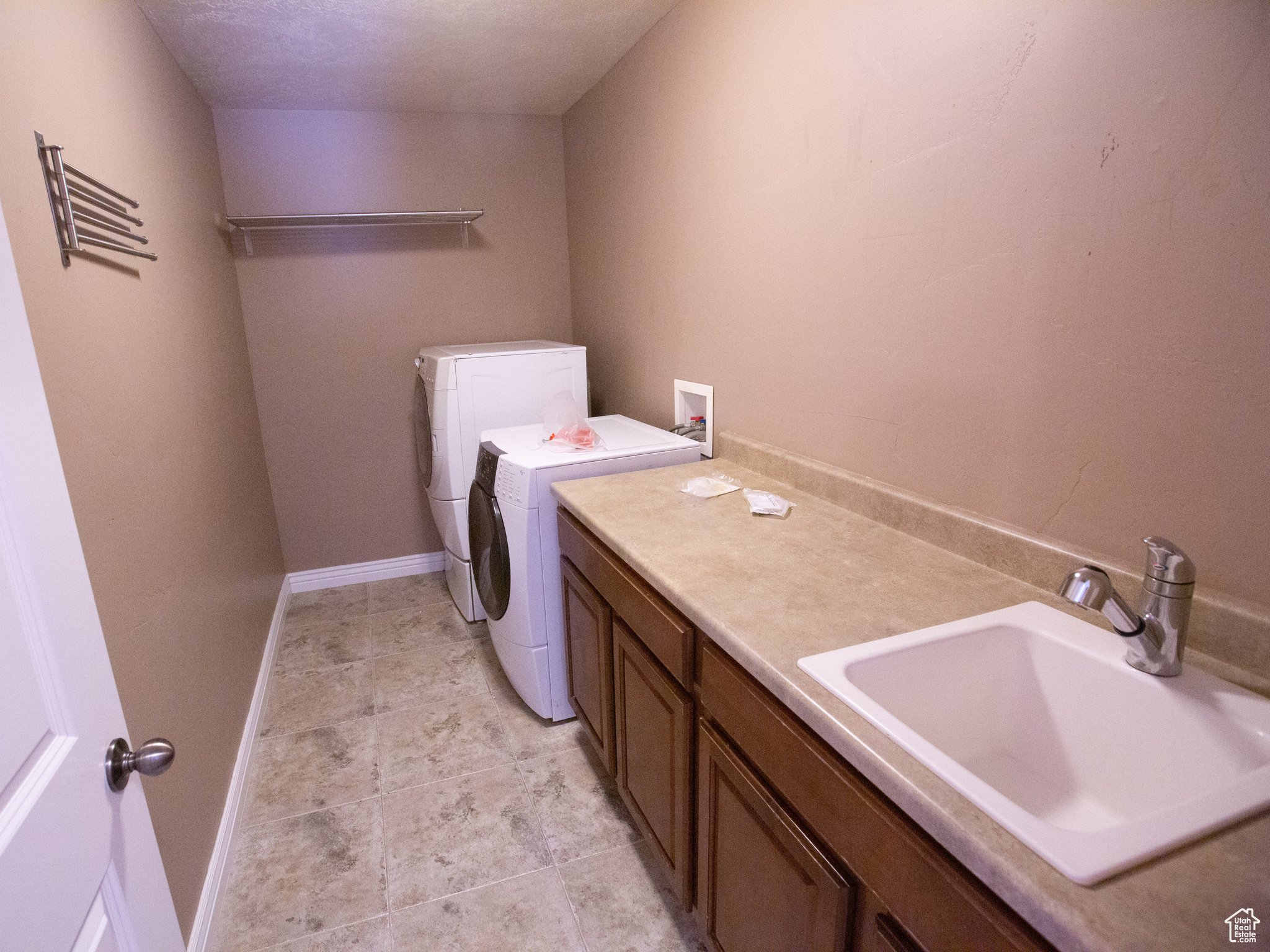 Washroom featuring light tile flooring, washer hookup, washing machine and clothes dryer, sink, and cabinets