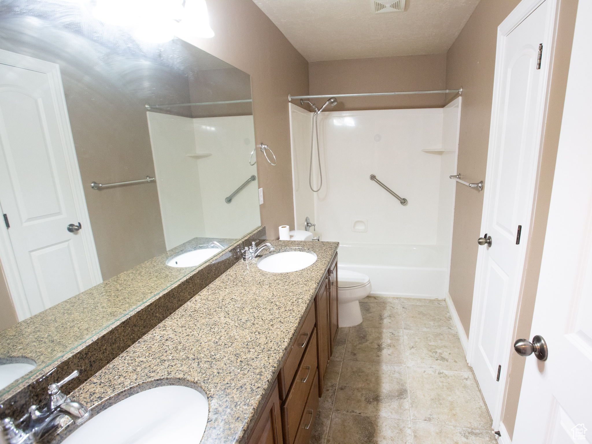 Full bathroom featuring tile flooring, washtub / shower combination, toilet, and double sink vanity