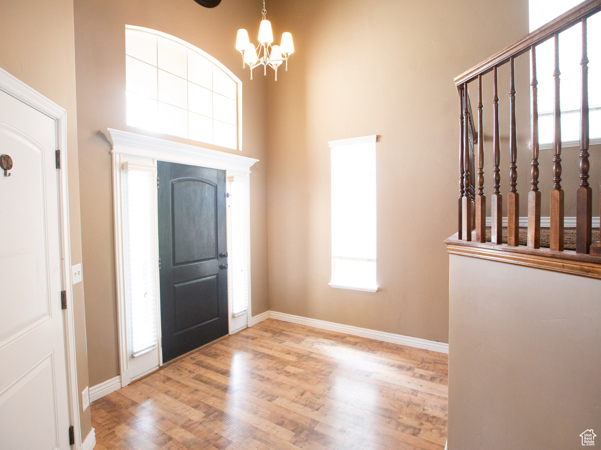 Foyer entrance with a high ceiling, light wood-type flooring, and an inviting chandelier