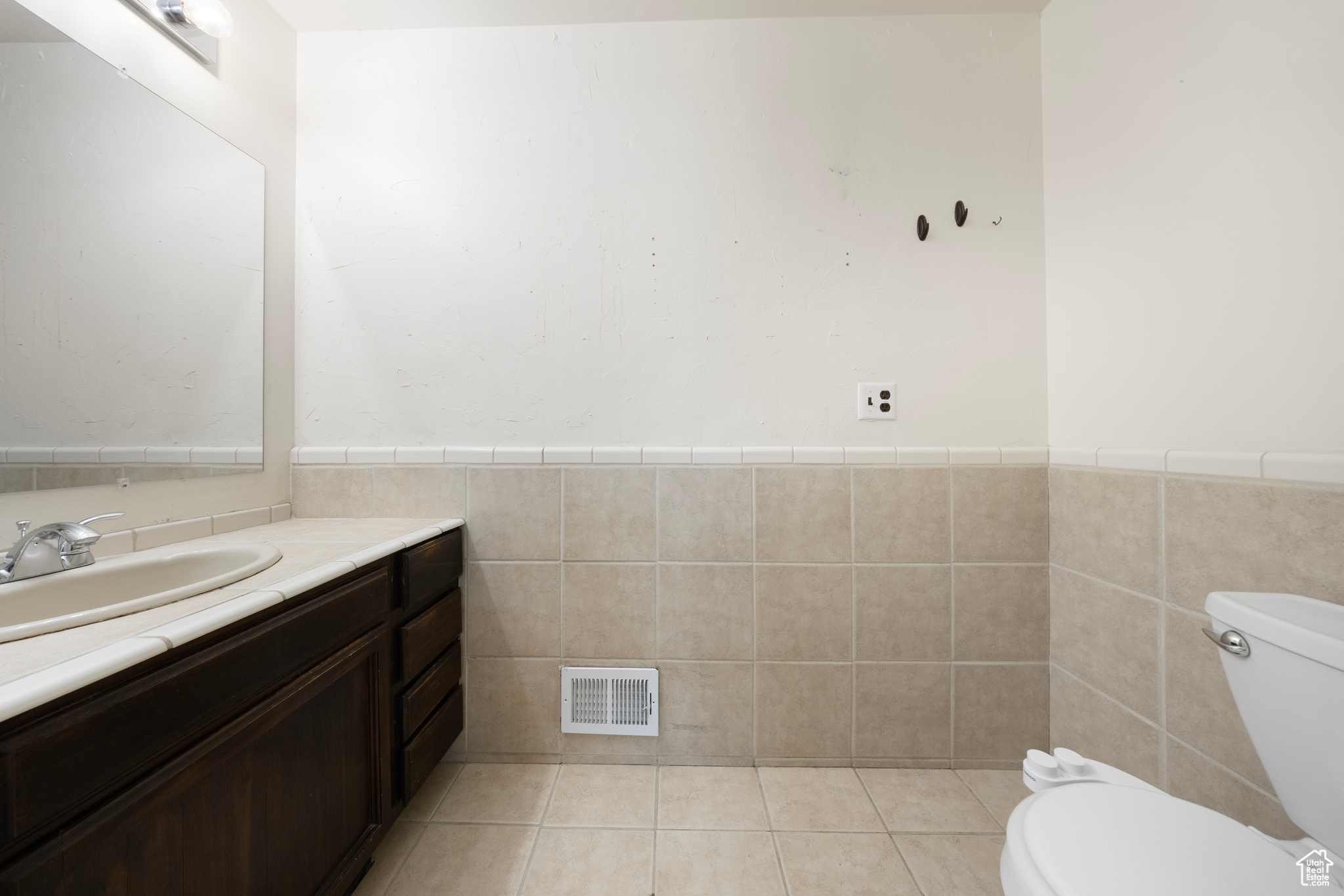Bathroom featuring vanity, toilet, tile floors, and tile walls