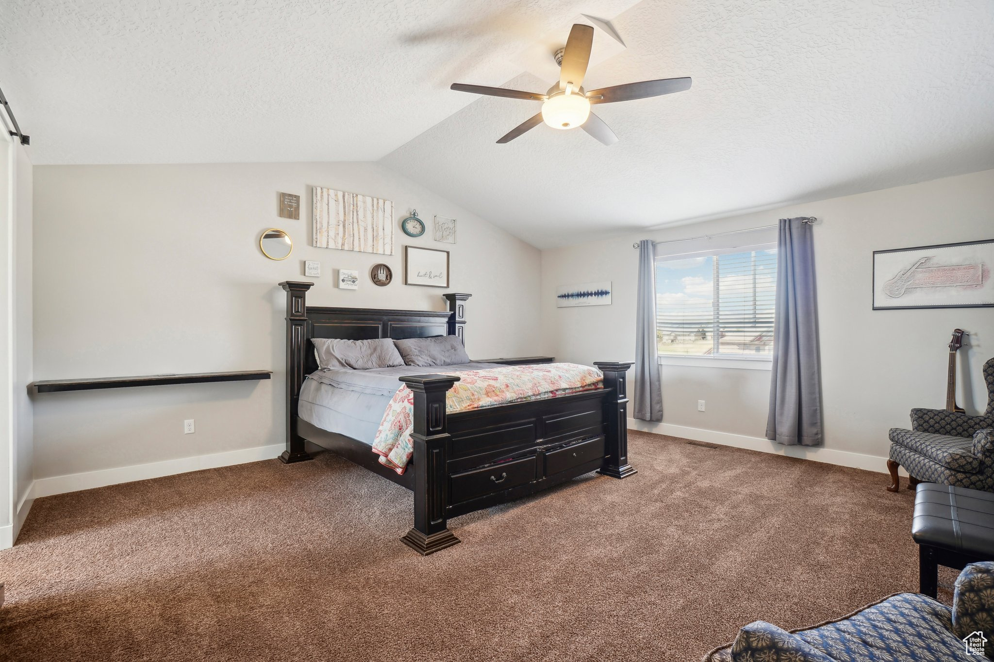 Carpeted bedroom with ceiling fan, a textured ceiling, and lofted ceiling