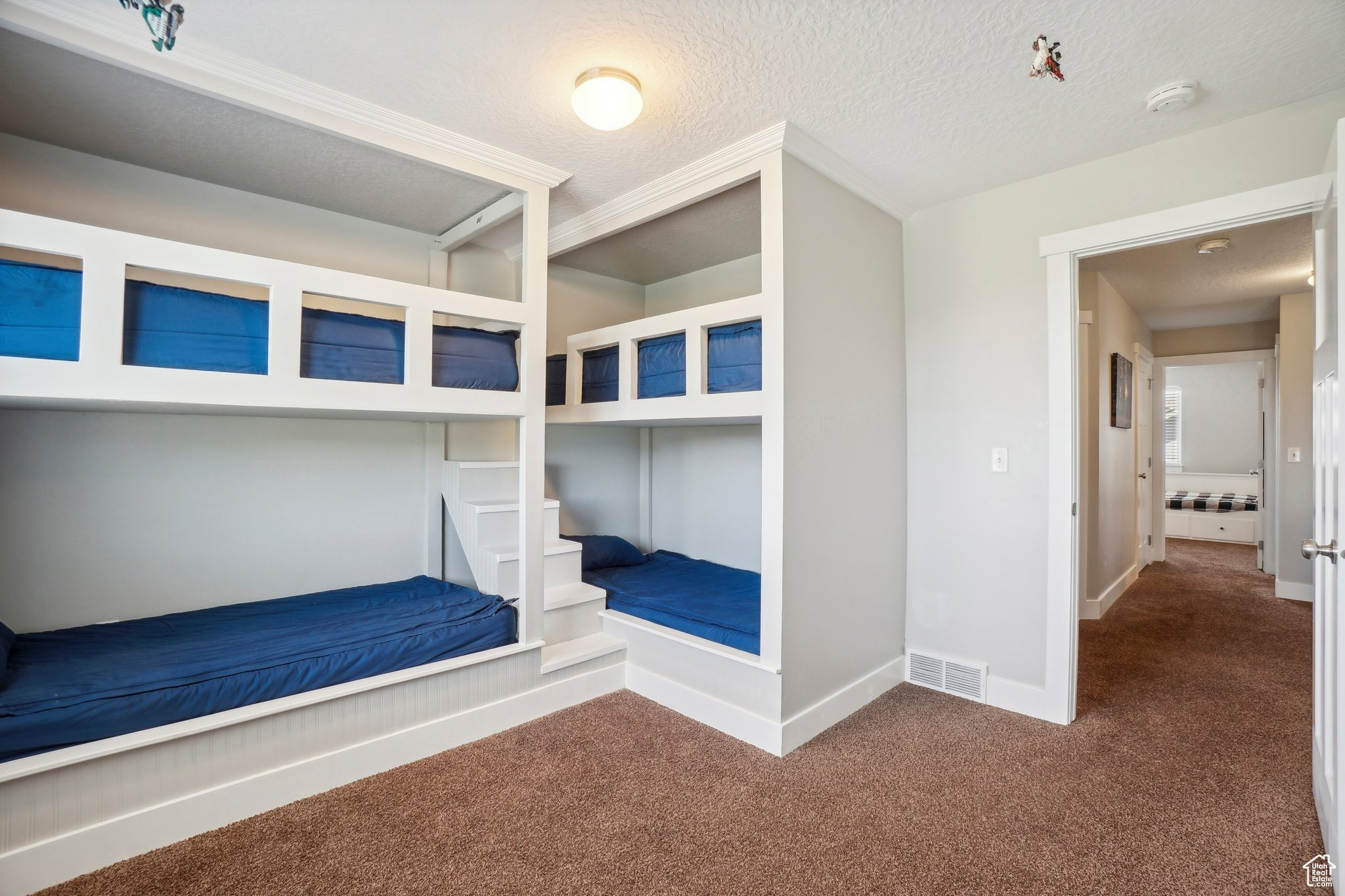 Unfurnished bedroom with dark colored carpet and a textured ceiling