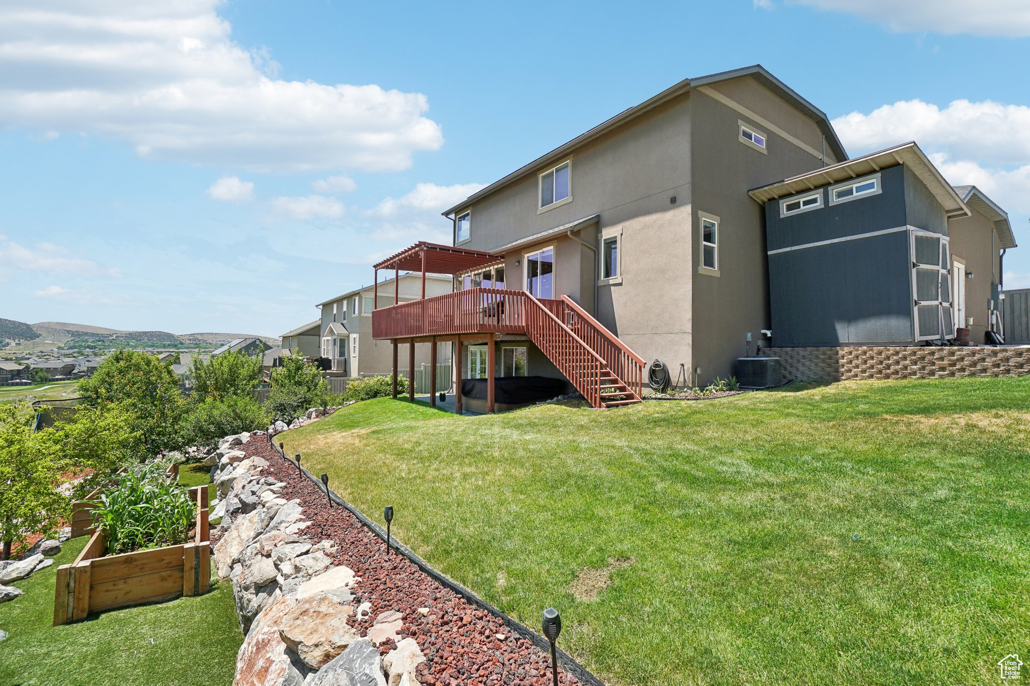 Rear view of property featuring a deck, central AC, and a lawn