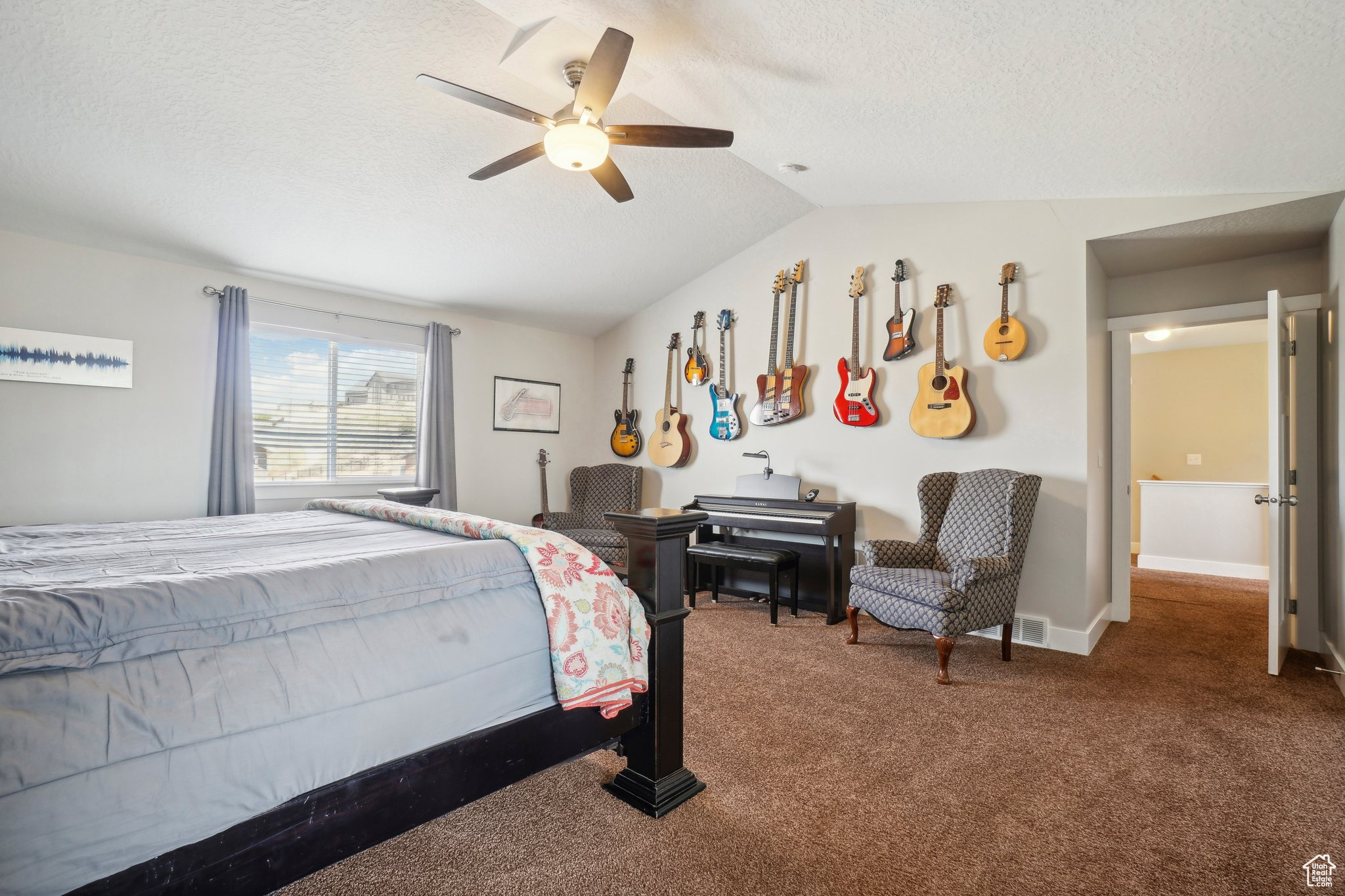 Carpeted bedroom with ceiling fan, a textured ceiling, and lofted ceiling