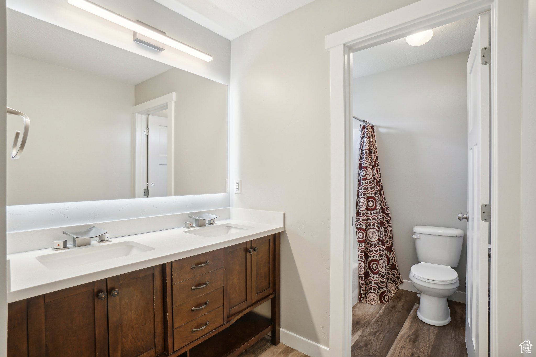 Bathroom with dual vanity, toilet, and hardwood / wood-style flooring