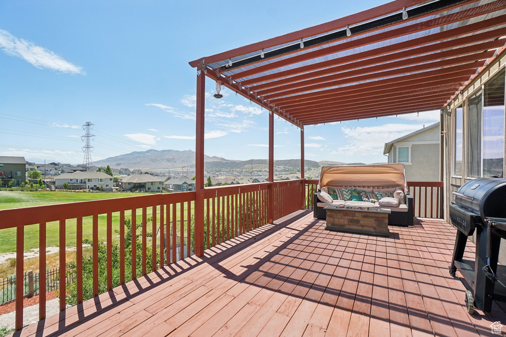 Wooden deck with a pergola, a mountain view, and a lawn