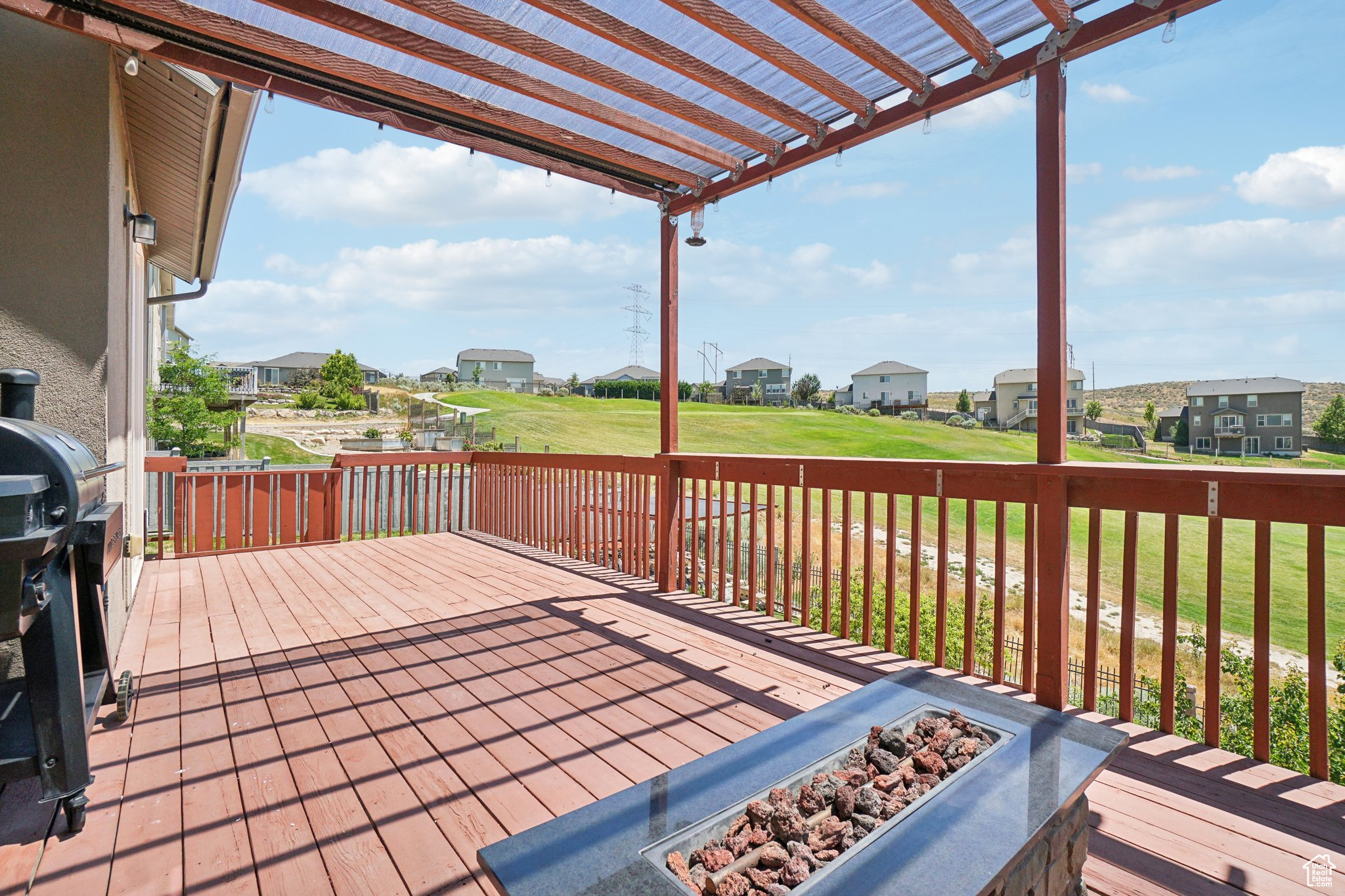 Wooden deck featuring a pergola, a fire pit, and a yard