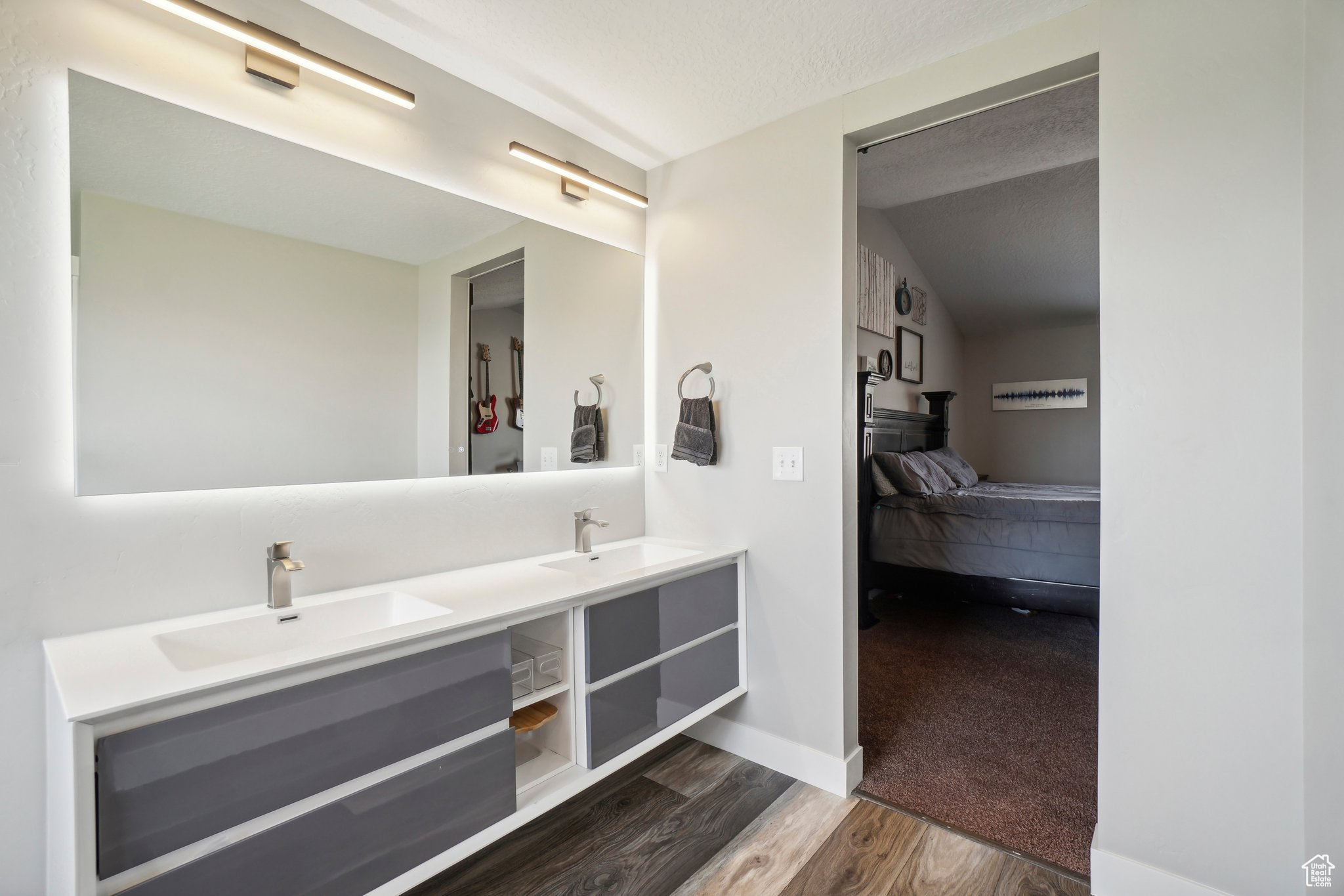 Bathroom with vaulted ceiling, wood-type flooring, oversized vanity, and double sink