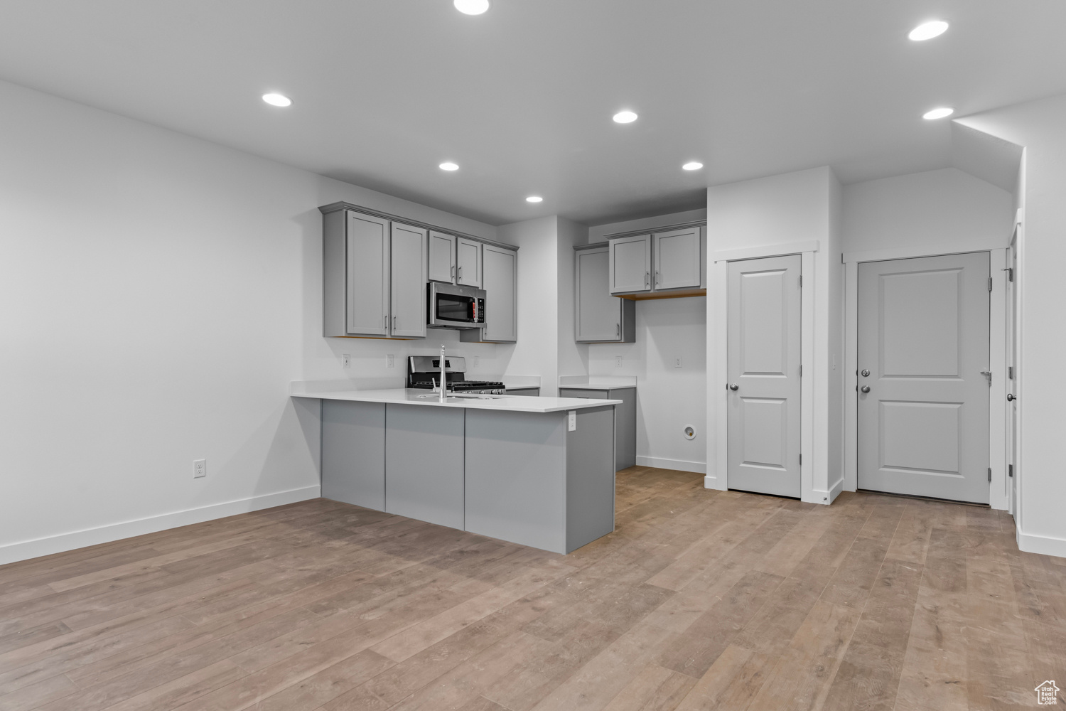 Kitchen with gas range, kitchen peninsula, light wood-type flooring, and gray cabinets