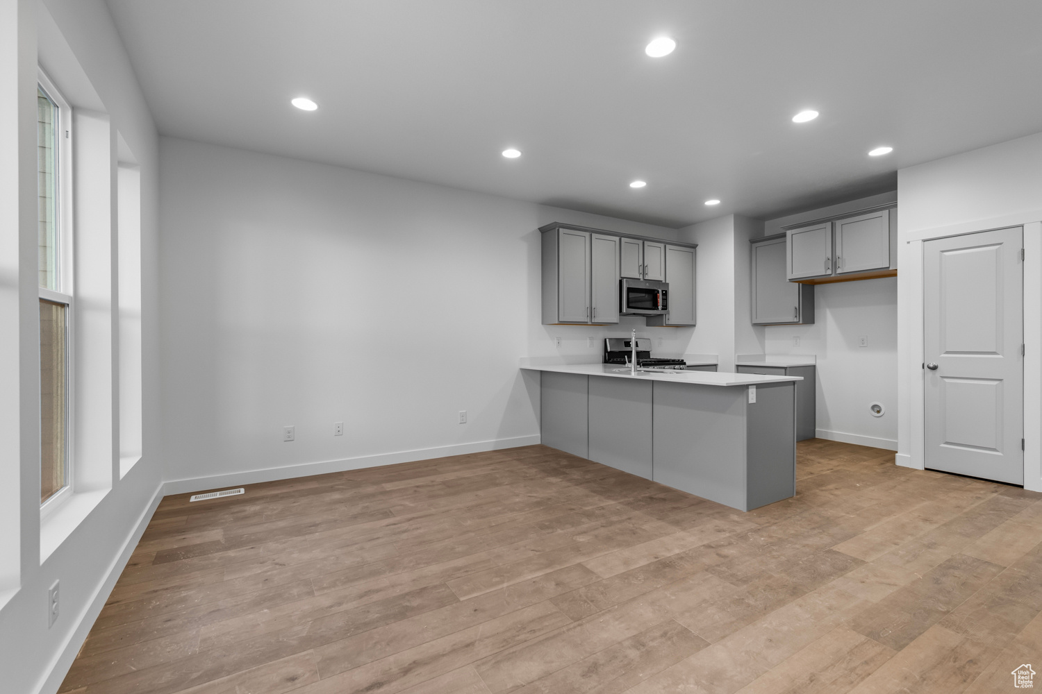 Kitchen with kitchen peninsula, light hardwood / wood-style flooring, a healthy amount of sunlight, and gas range