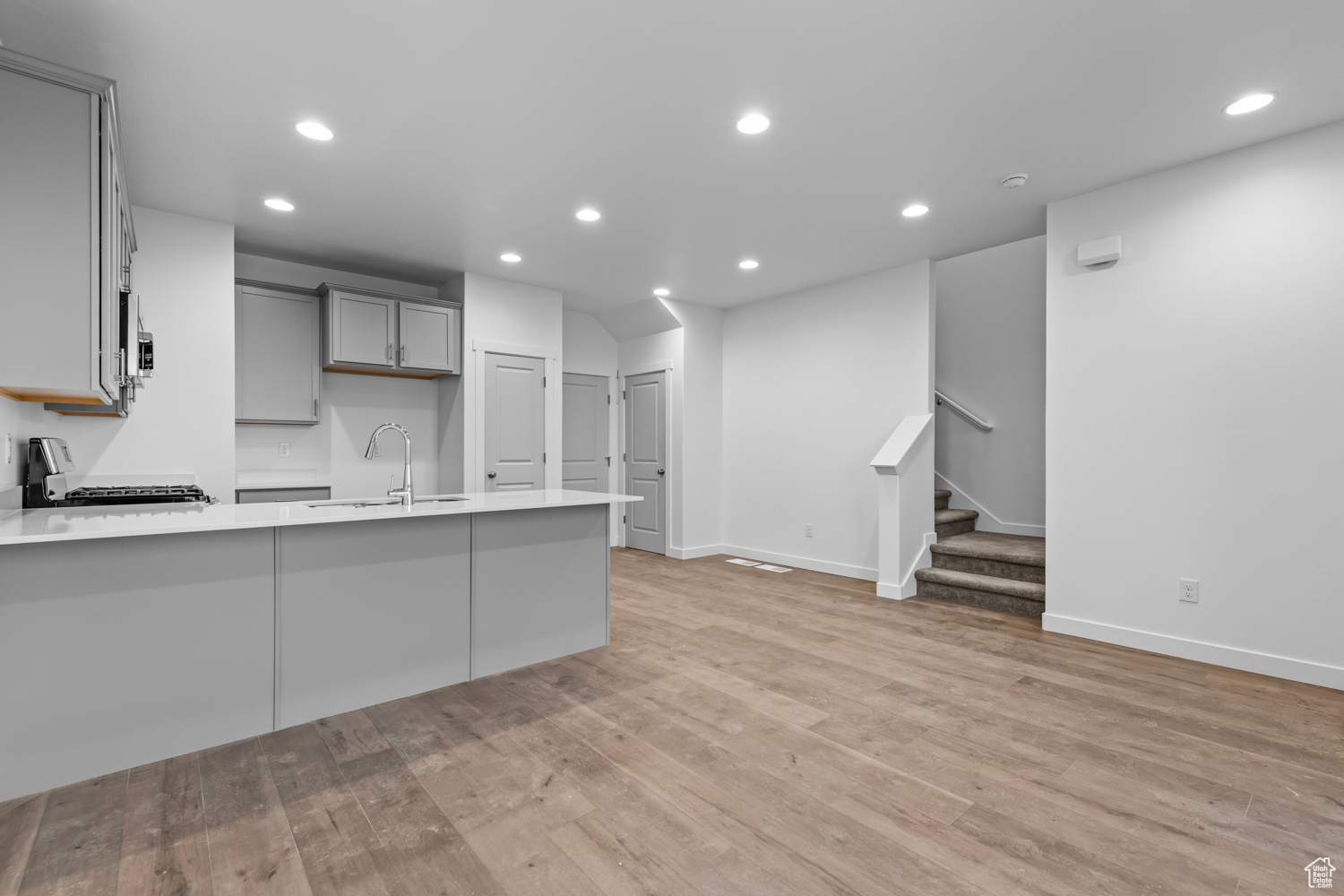 Kitchen with sink, gray cabinetry, light wood-type flooring, and range