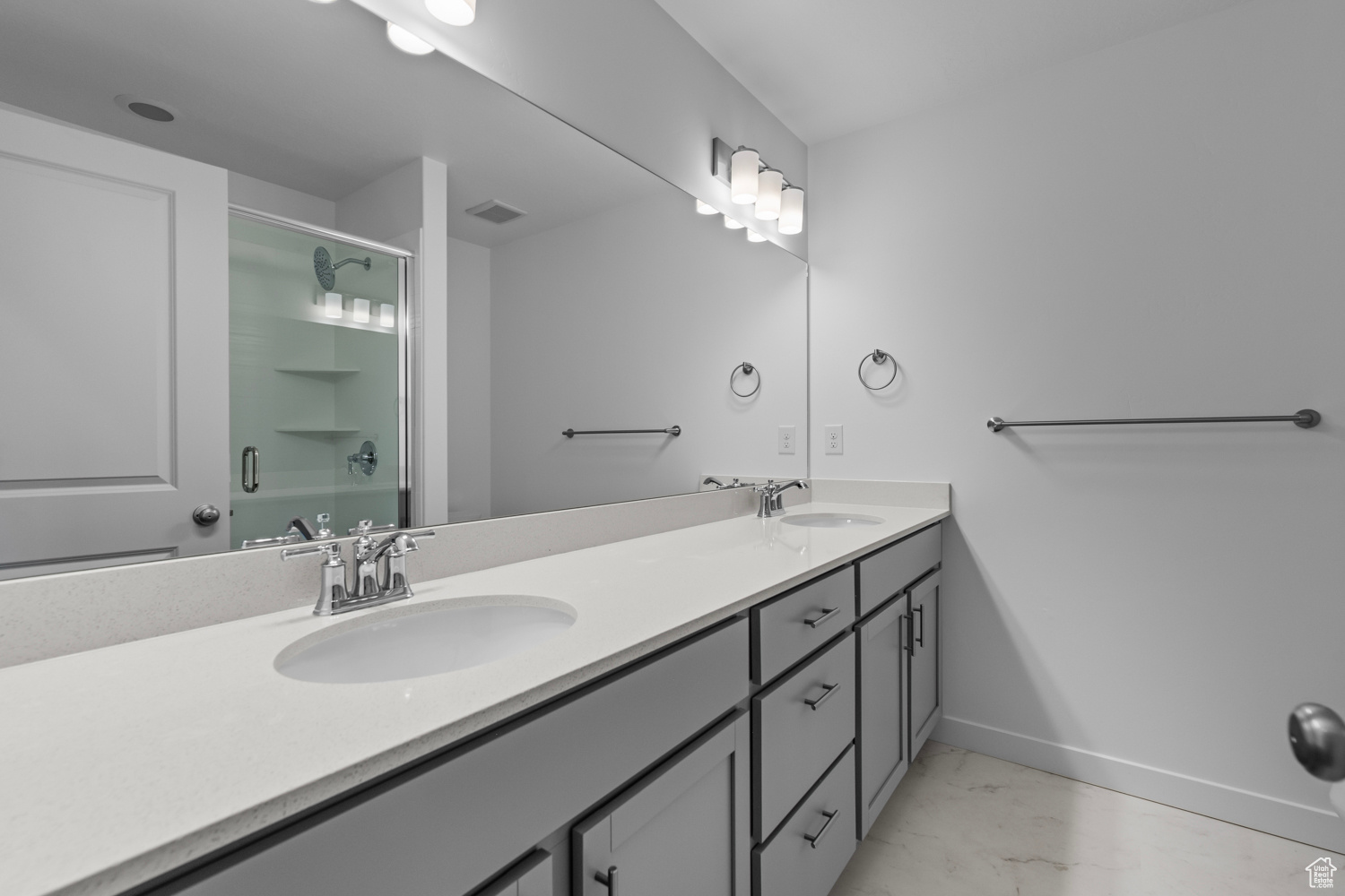 Bathroom with vanity with extensive cabinet space, double sink, and tile flooring