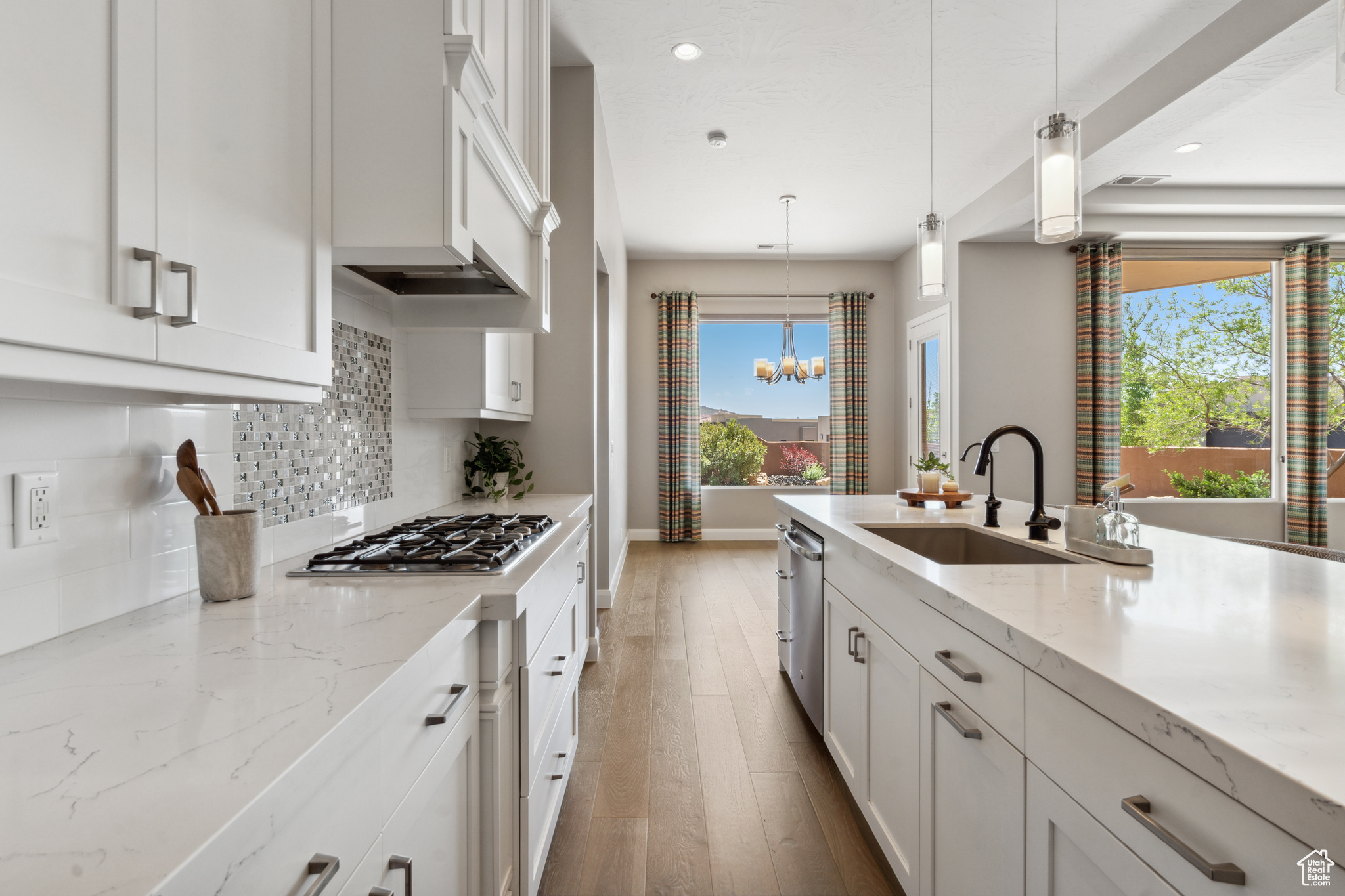 Kitchen featuring a wealth of natural light, hanging light fixtures, white cabinetry, and backsplash