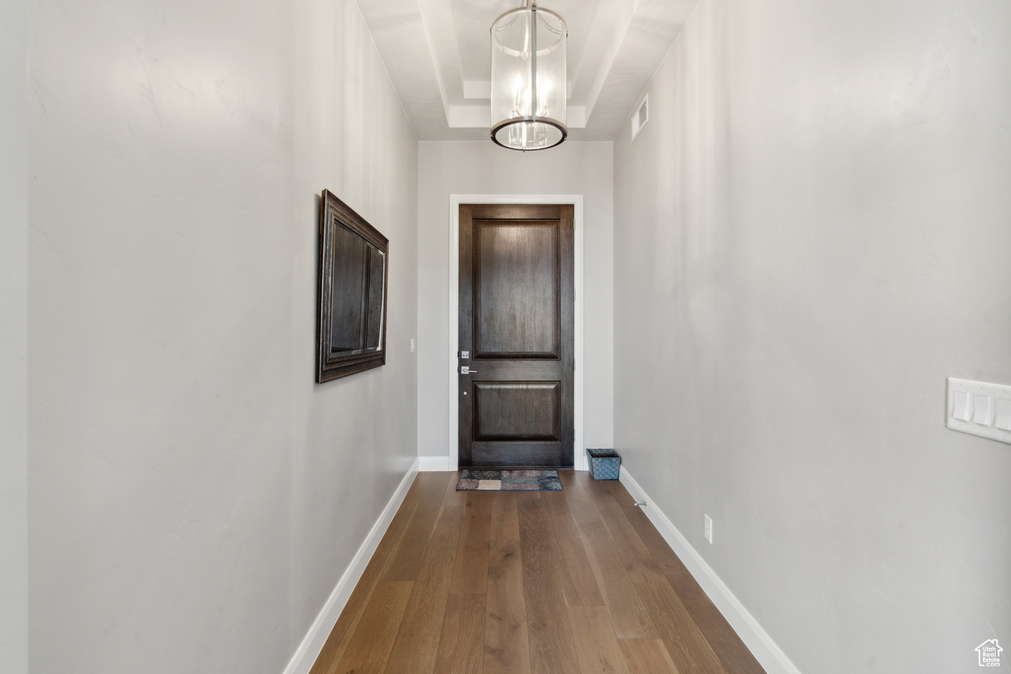 Doorway to outside with a raised ceiling, a chandelier, and hardwood / wood-style flooring