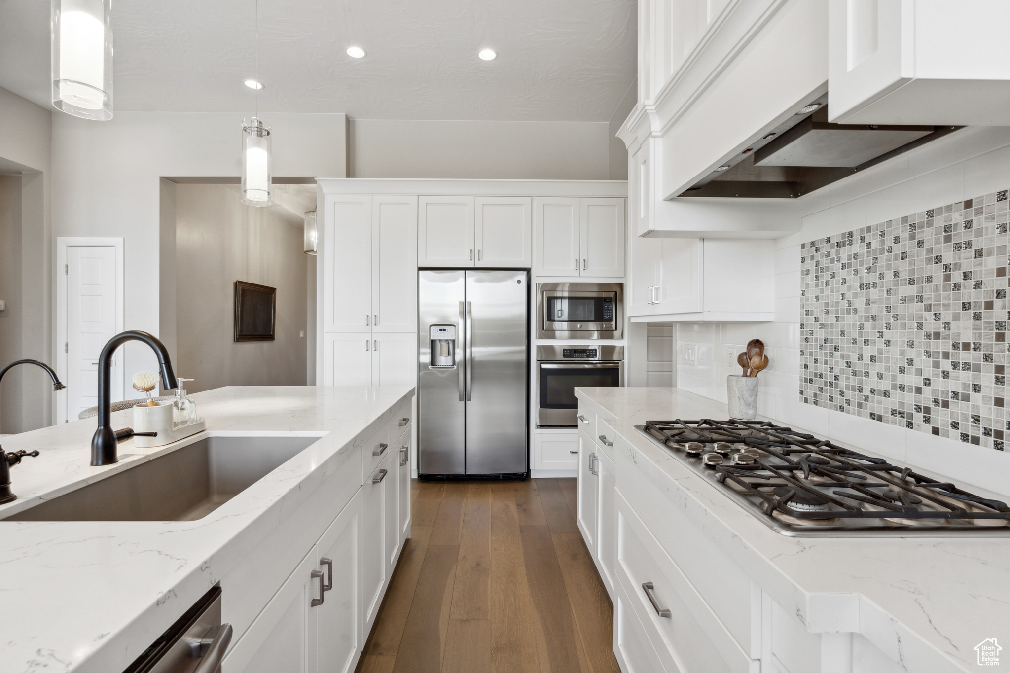 Kitchen with decorative light fixtures, dark hardwood / wood-style floors, appliances with stainless steel finishes, sink, and tasteful backsplash