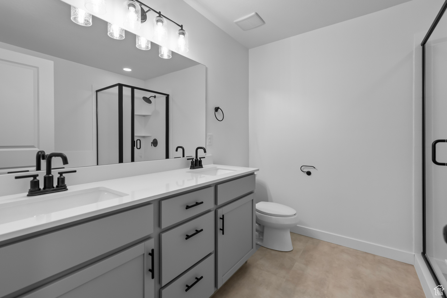 Bathroom featuring tile flooring, double vanity, toilet, and a shower with door