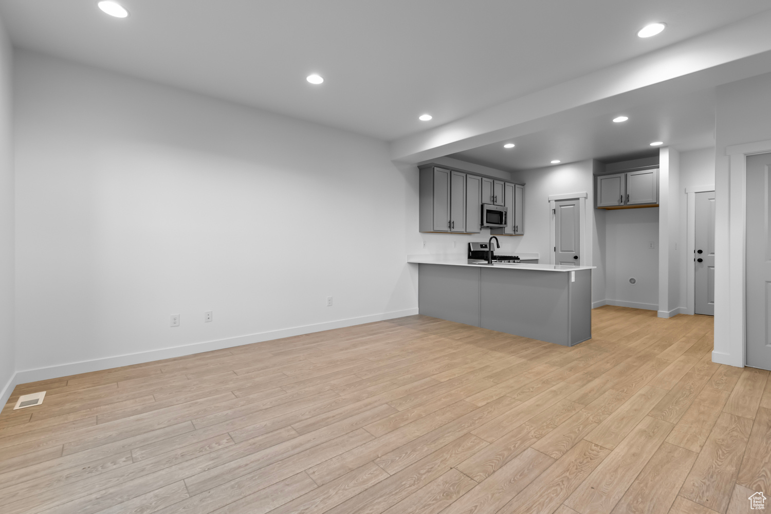 Kitchen featuring light hardwood / wood-style flooring, gray cabinetry, stainless steel appliances, and kitchen peninsula