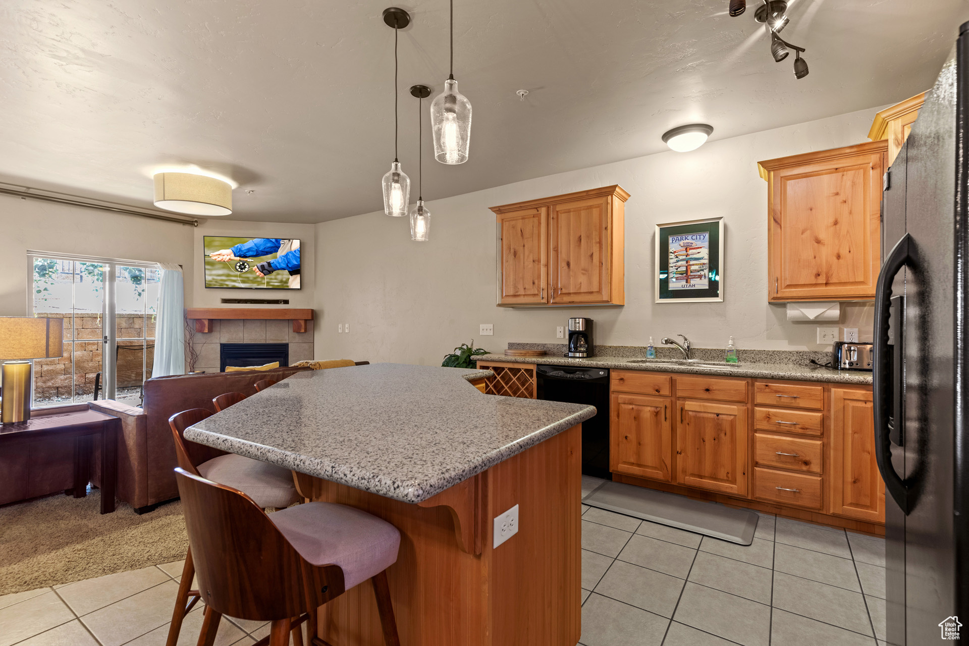 Kitchen featuring a tile fireplace, light tile floors, sink, decorative light fixtures, and black appliances