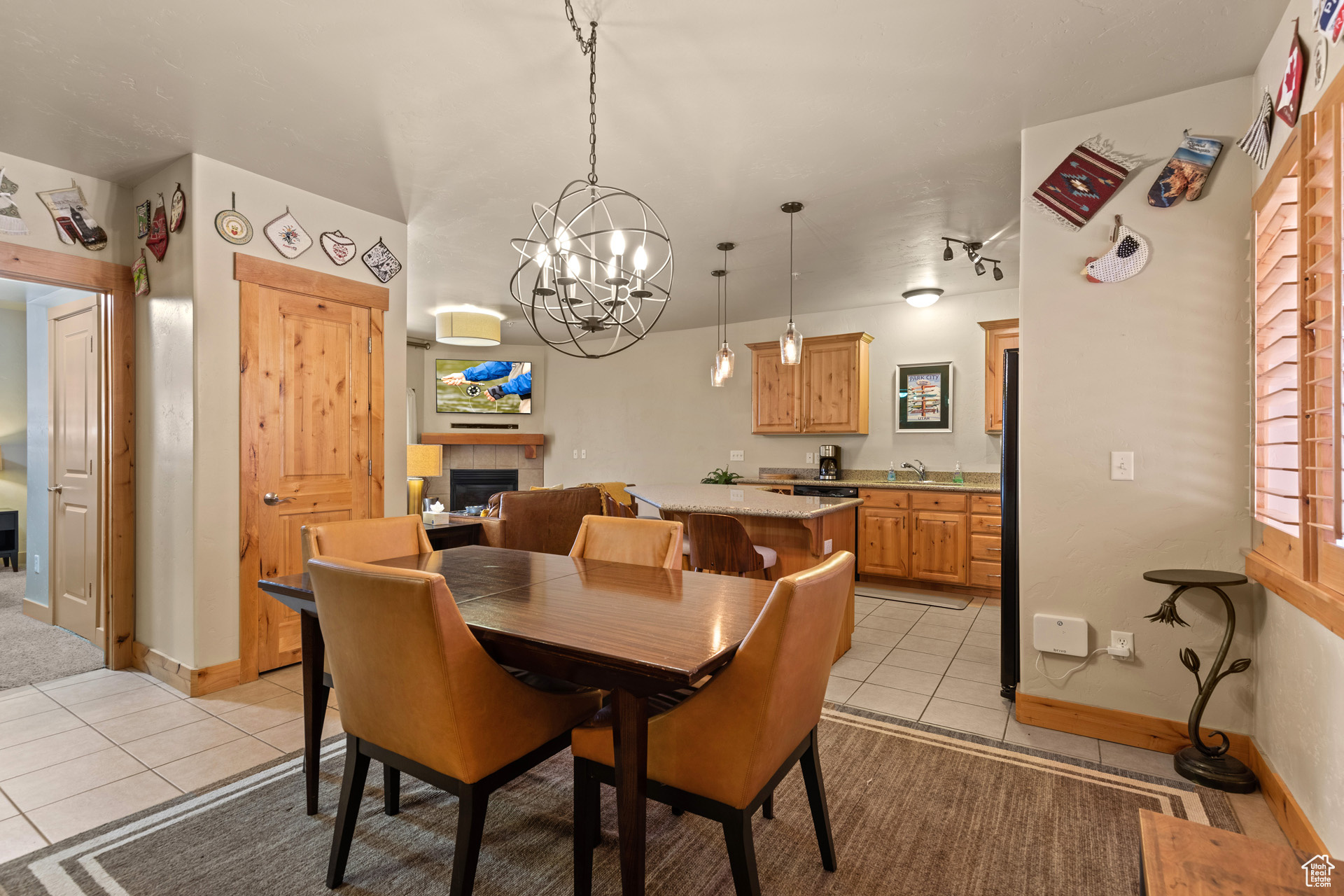 Dining space featuring a chandelier, light tile floors, and a tiled fireplace