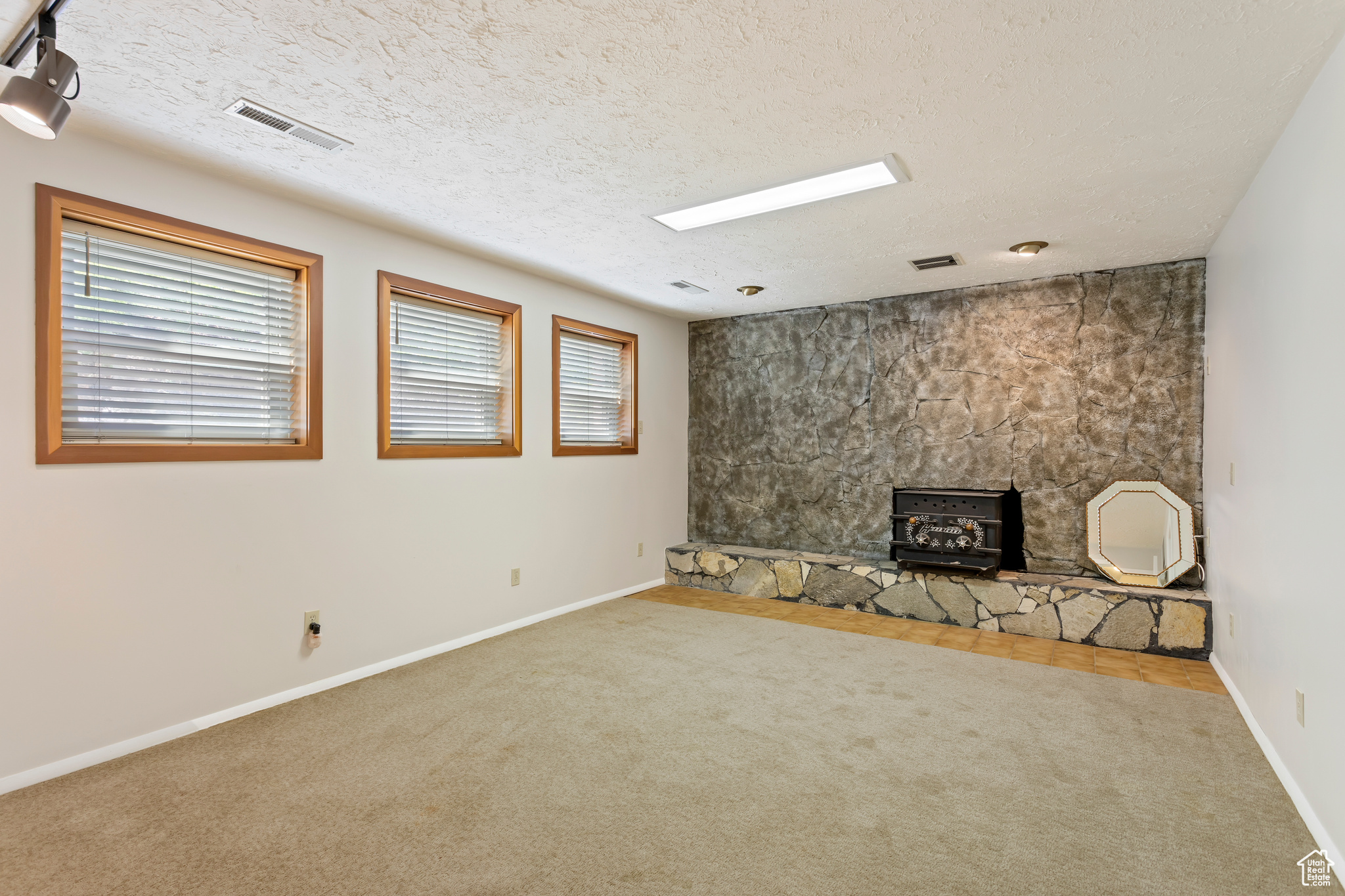 Interior space with a textured ceiling, carpet floors, a fireplace, and a wood stove