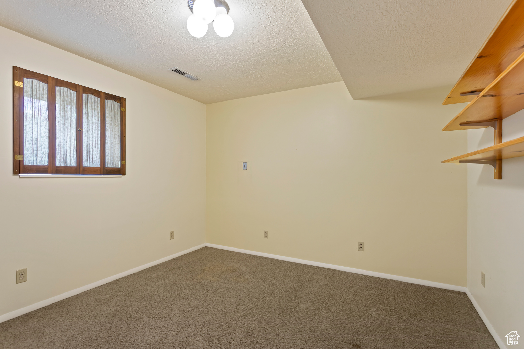 Carpeted empty room featuring a textured ceiling