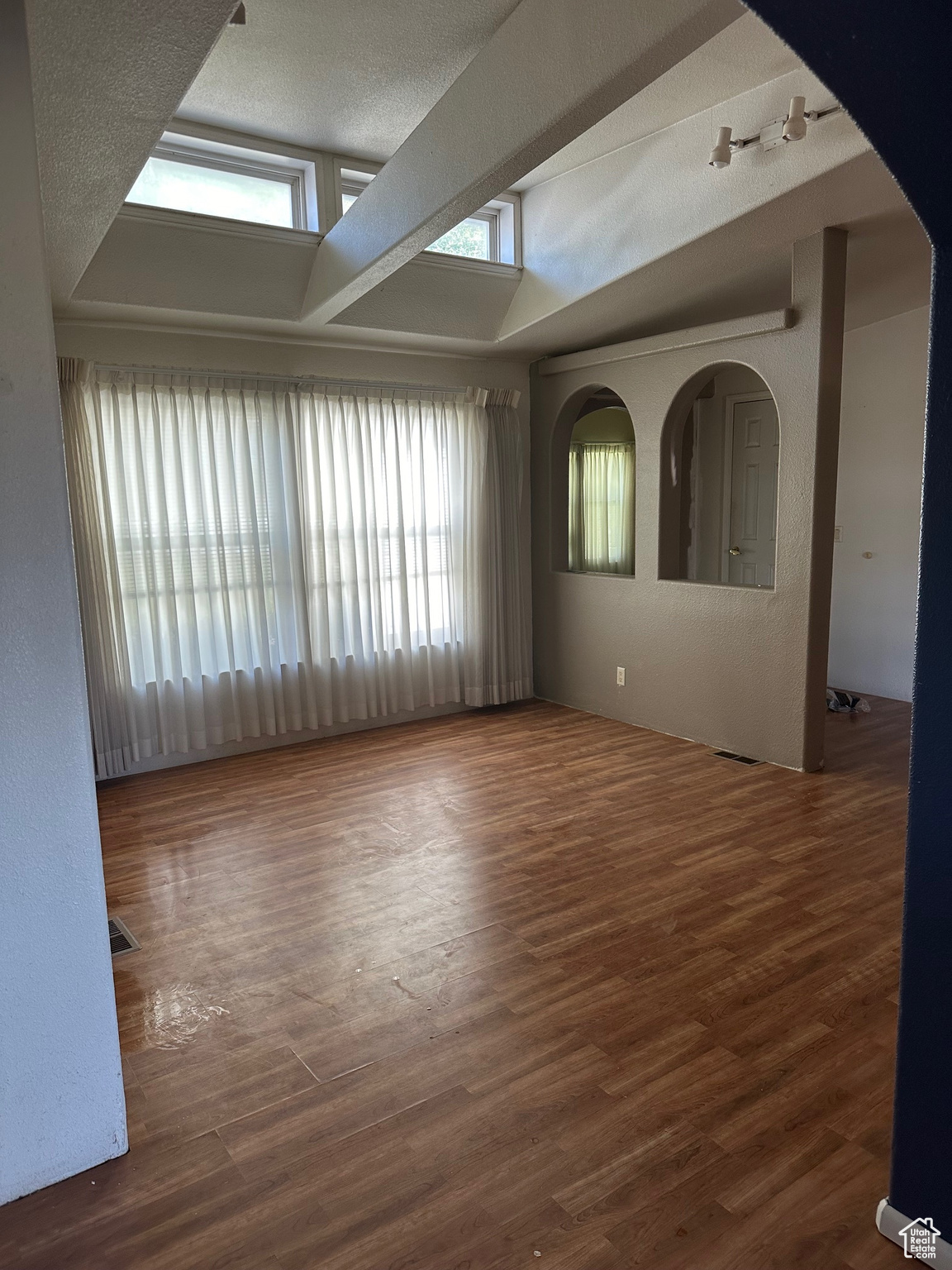 Unfurnished room featuring a textured ceiling, lofted ceiling, and wood-type flooring