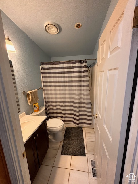 Bathroom featuring tile patterned floors, toilet, a textured ceiling, and vanity