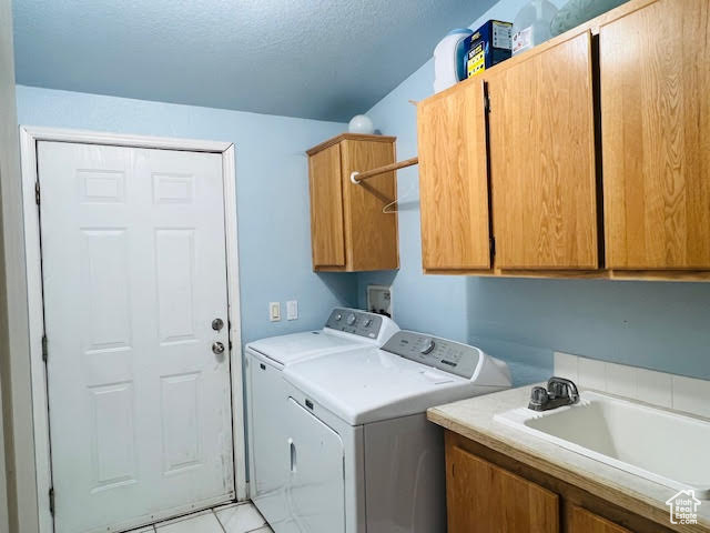 Laundry room featuring sink, cabinets, a textured ceiling, light tile patterned floors, and independent washer and dryer