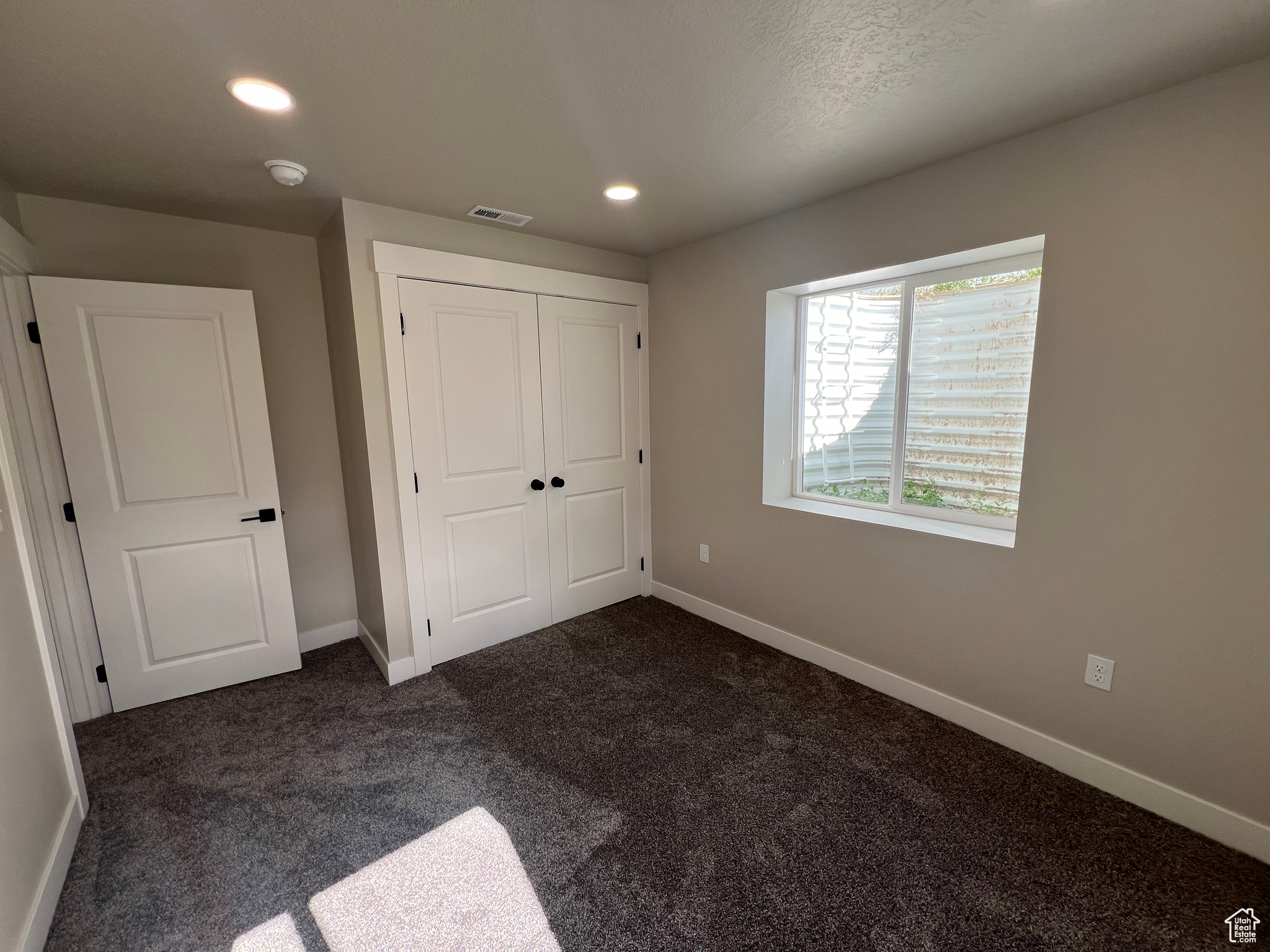 Unfurnished bedroom featuring a closet and dark colored carpet