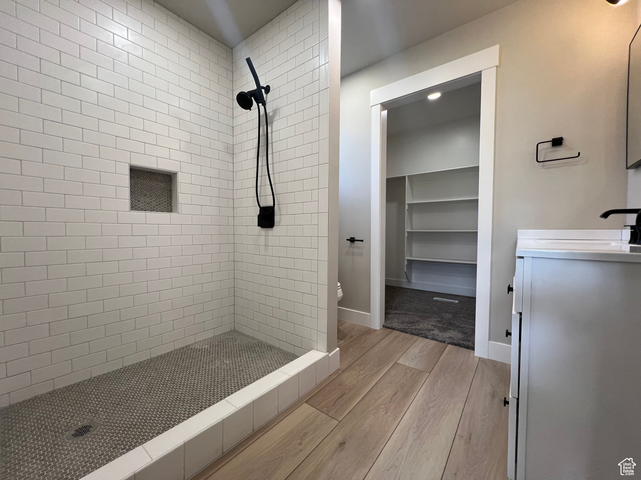 Bathroom featuring wood-type flooring, vanity, toilet, and a tile shower