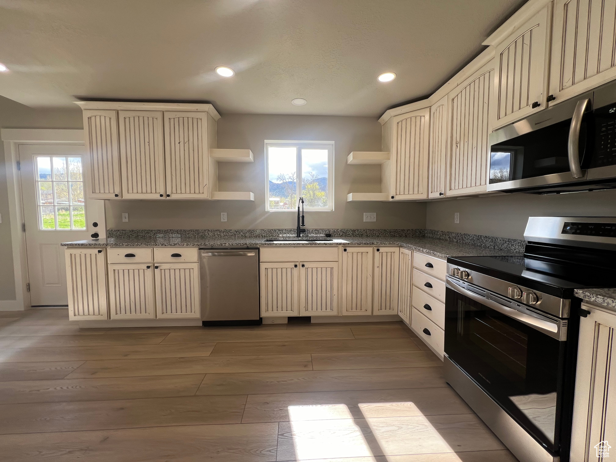 Kitchen with light hardwood / wood-style flooring, a wealth of natural light, stainless steel appliances, and sink