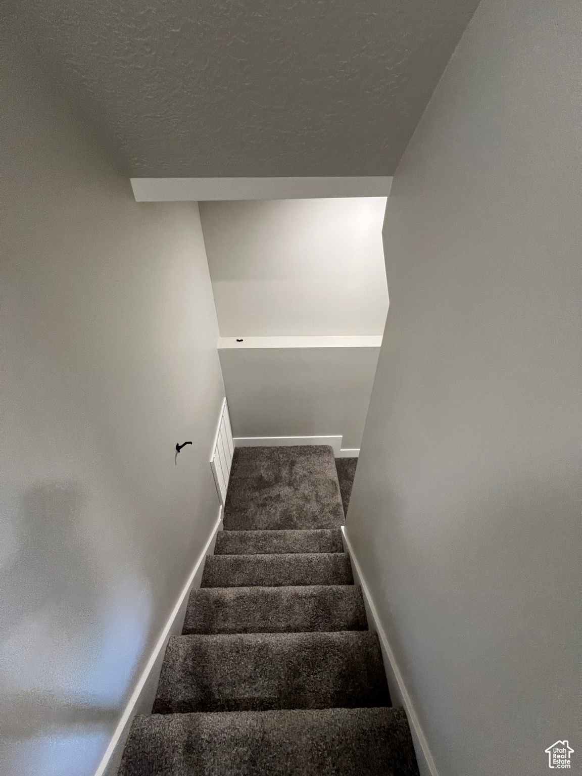 Stairs featuring dark carpet and a textured ceiling