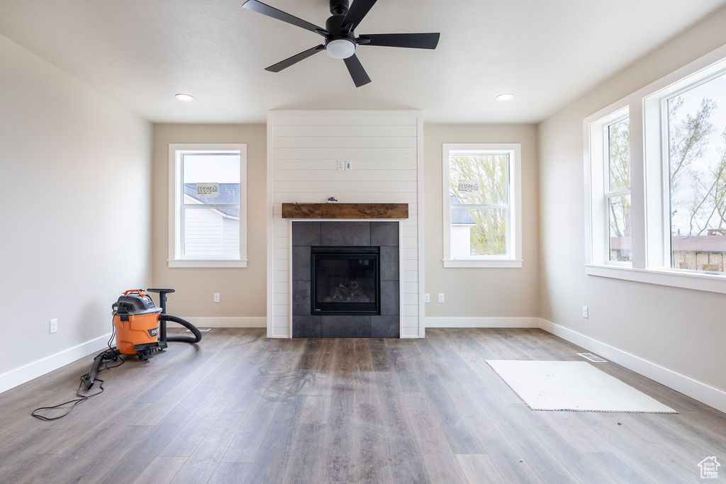Unfurnished living room featuring wood-type flooring, ceiling fan, and a tile fireplace