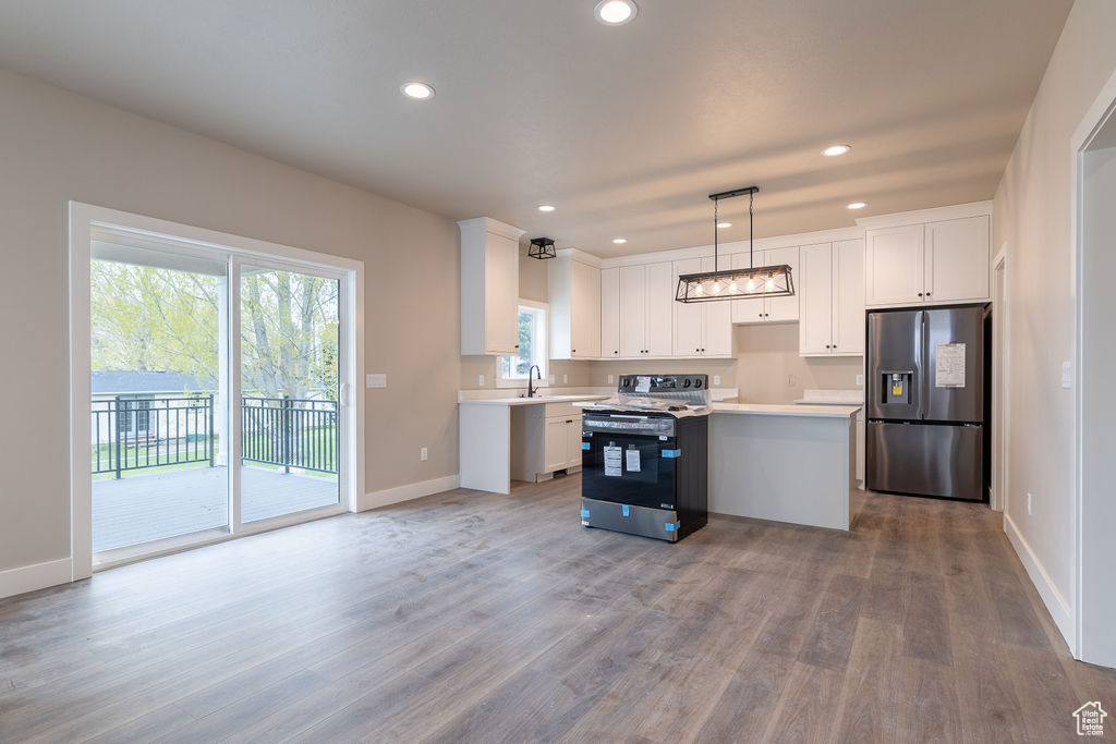 Kitchen featuring a kitchen island, hardwood / wood-style floors, decorative light fixtures, stainless steel fridge, and range with electric stovetop